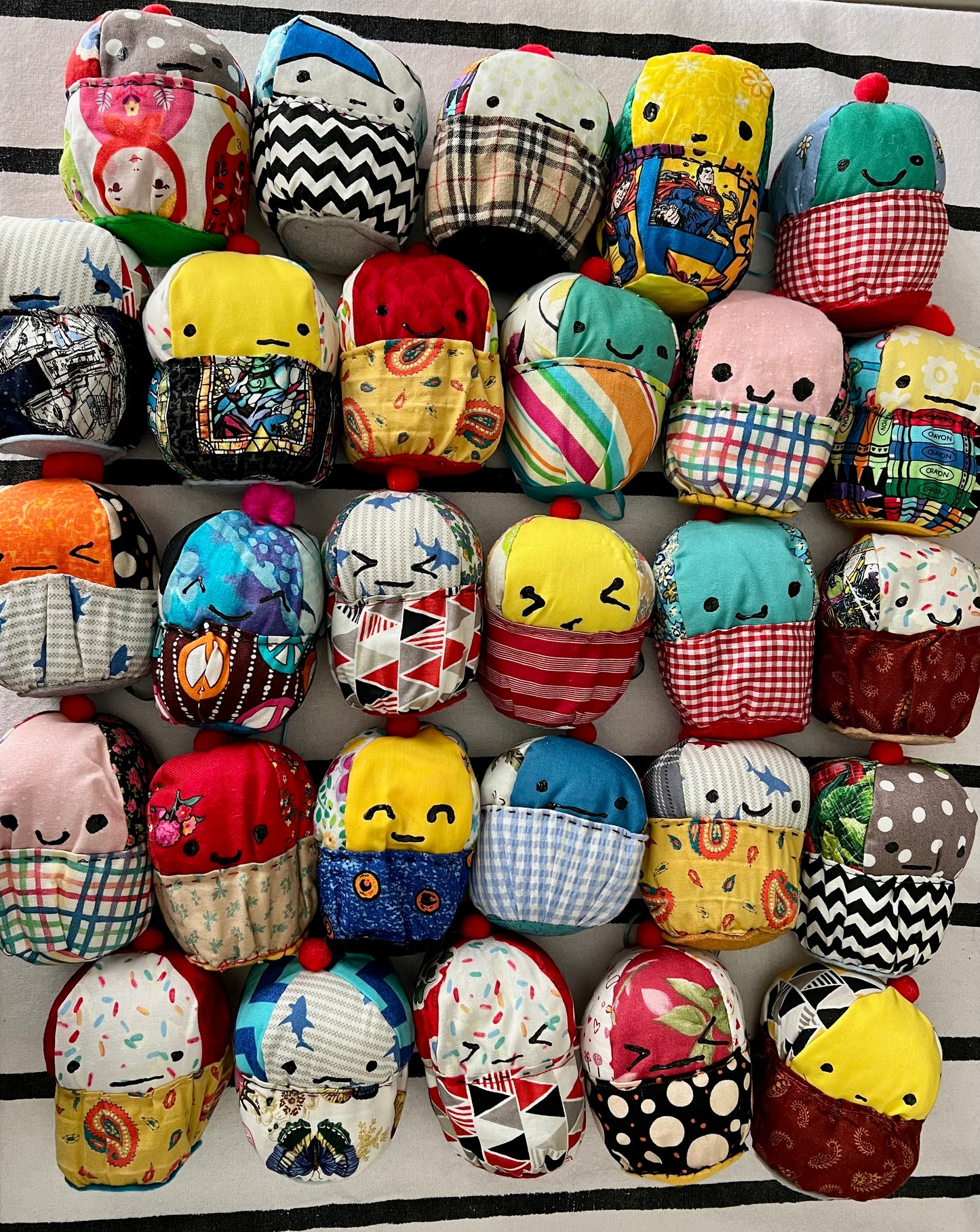 A group of colorful plush cupcakes. Looking real cute, with a striped background.