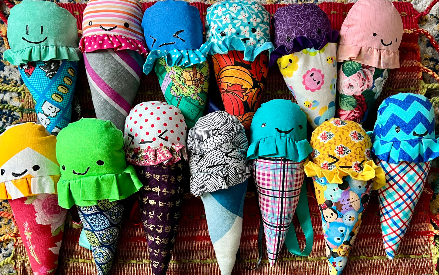 Collection of colorful fabric ice cream cones with faces on a patterned background