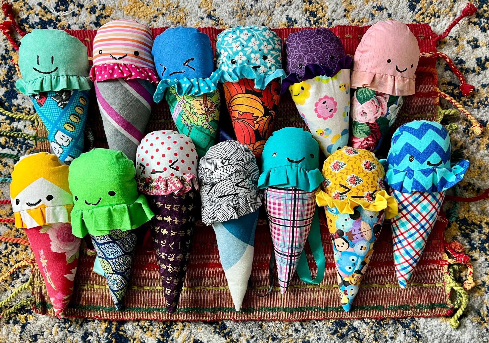 Colorful fabric ice cream cones with faces on a textured surface