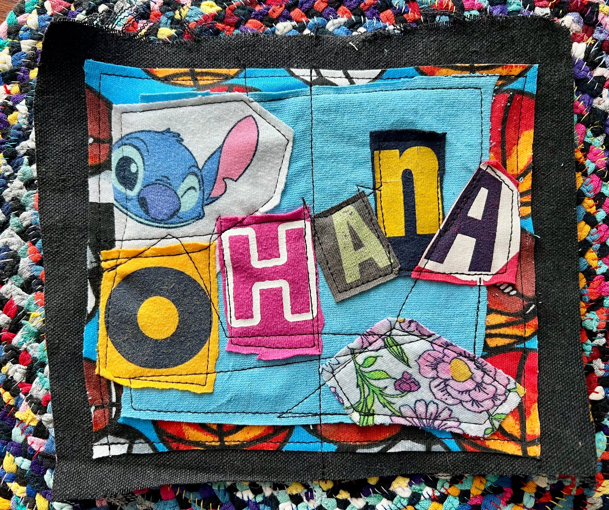 Patchwork square with colorful letters and a cartoon character on a textured background