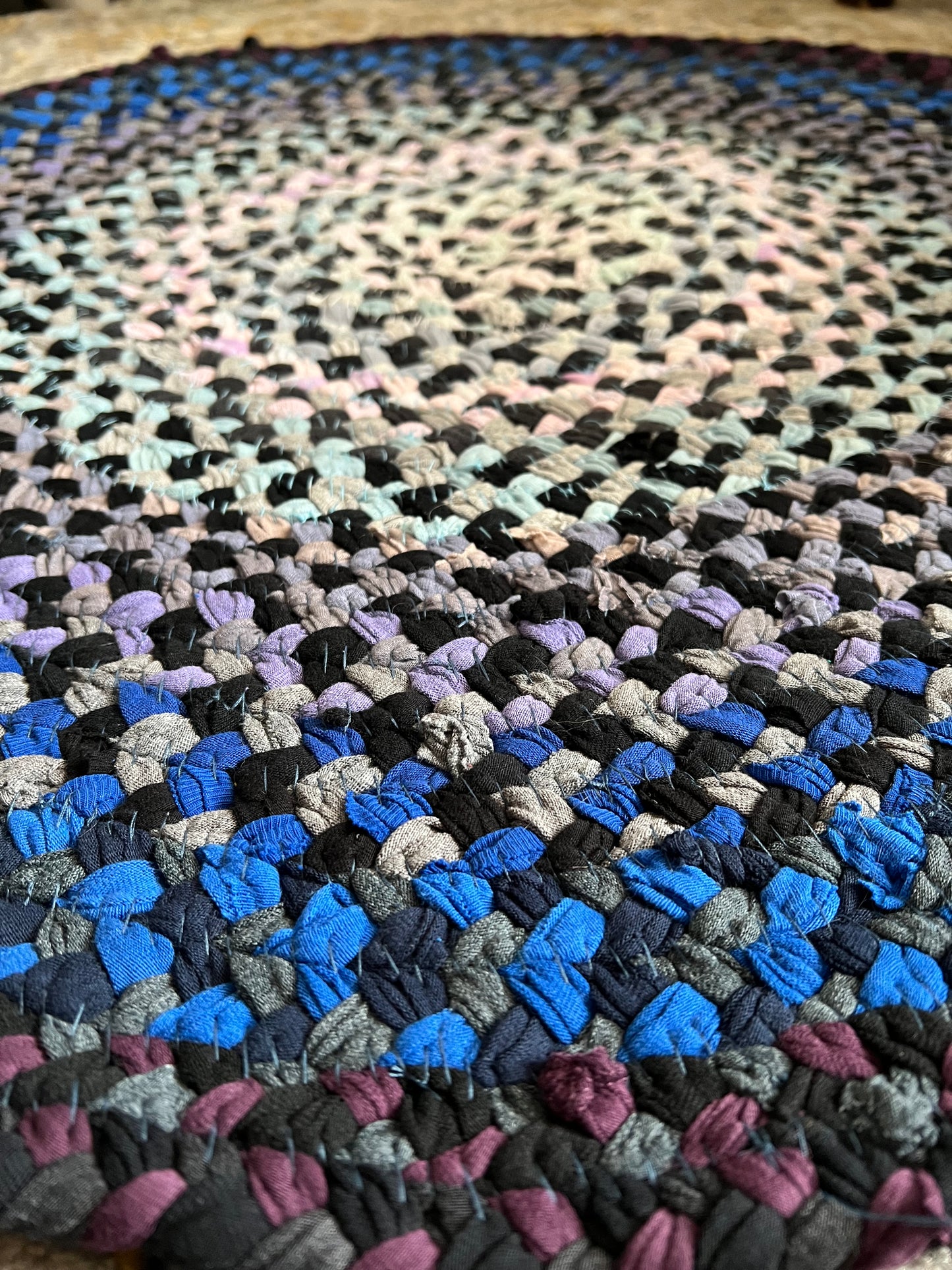 Close-up of a multicolored braided rug with an ombre pattern.