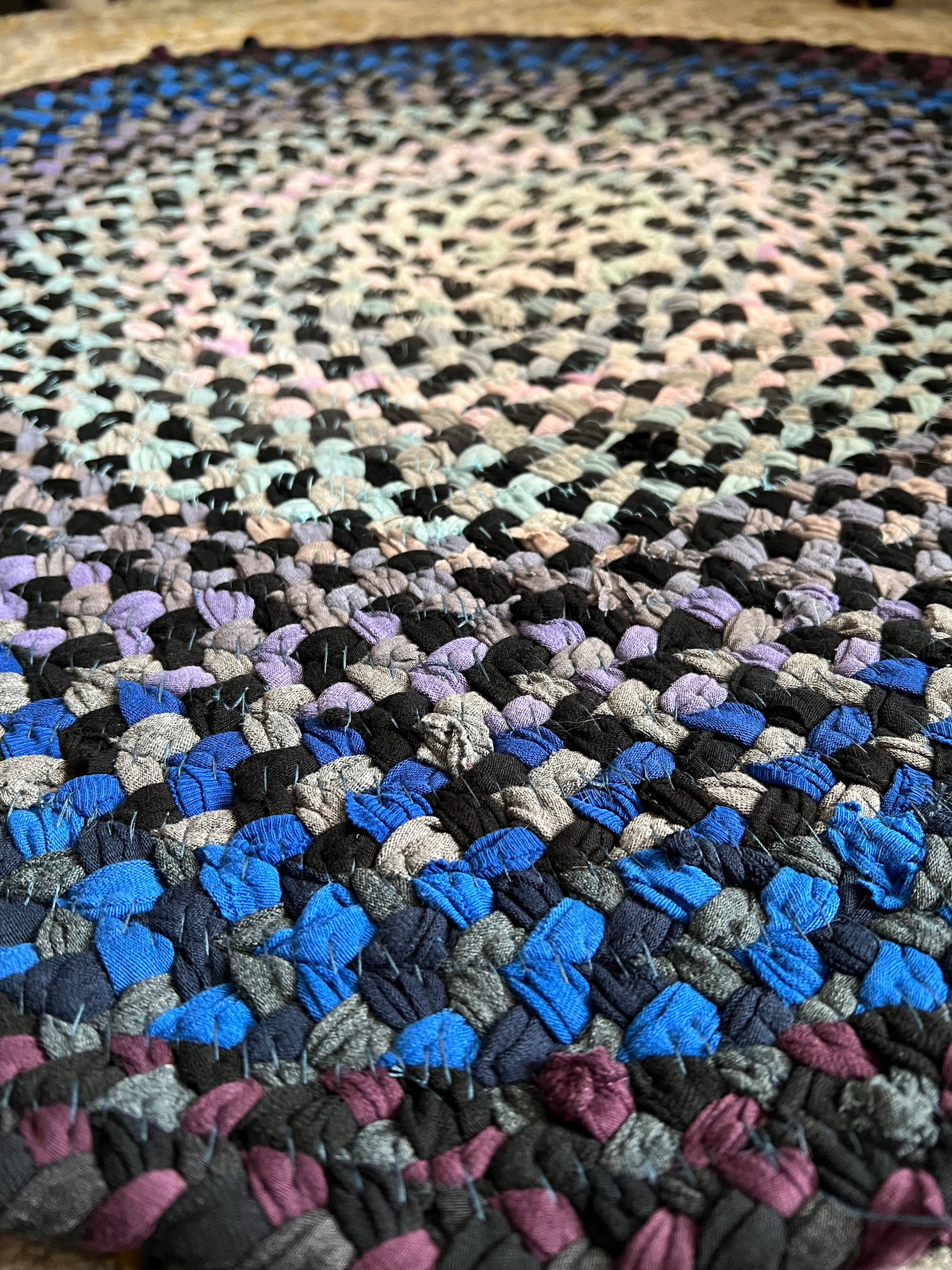 Close-up of a multicolored braided rug with an ombre pattern.
