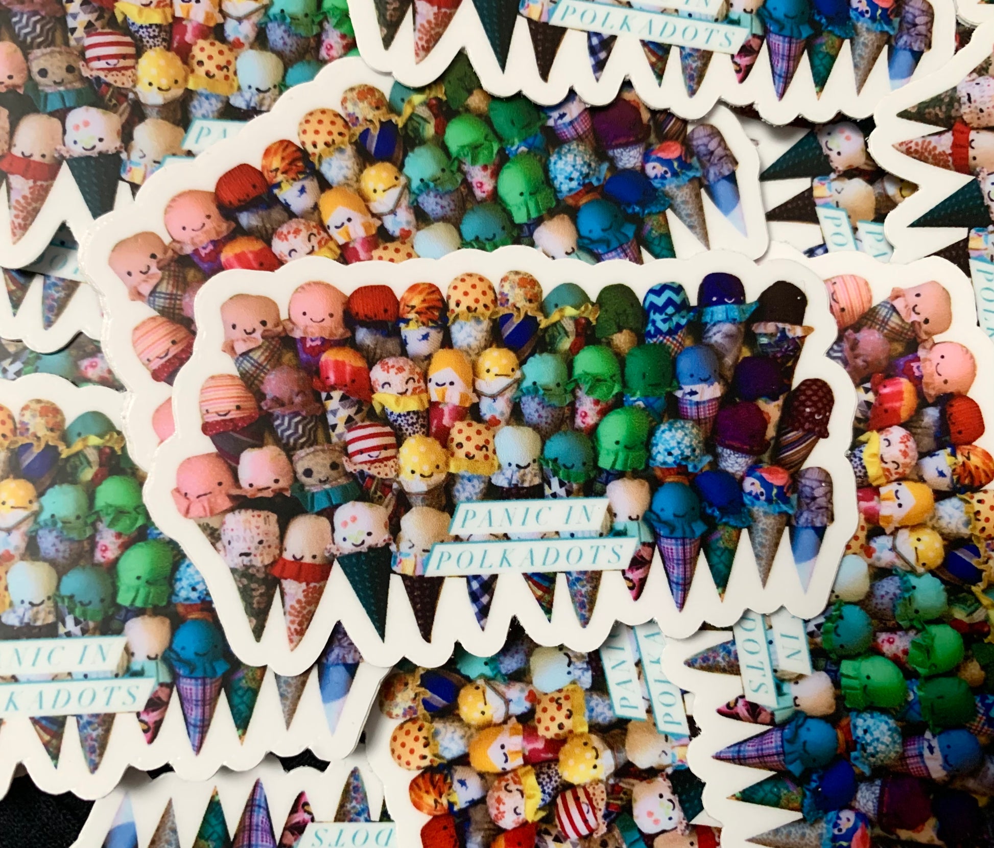 A rainbow of ice cream cones, group photo, with "Panic in Polkadots" over the bottom middle. Stack of stickers in a randomized pile