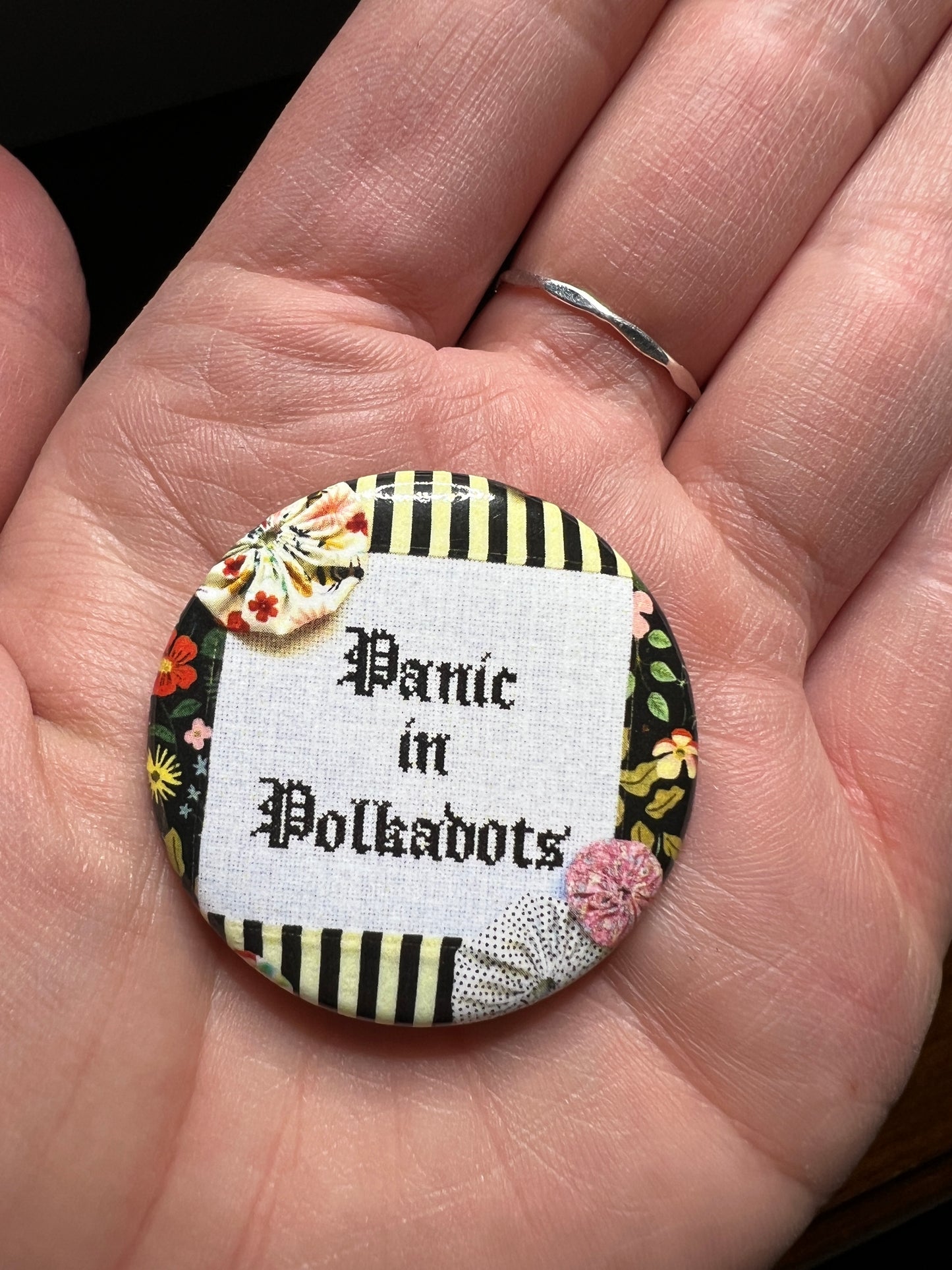 A single panic in polkadots button held in hand for scale