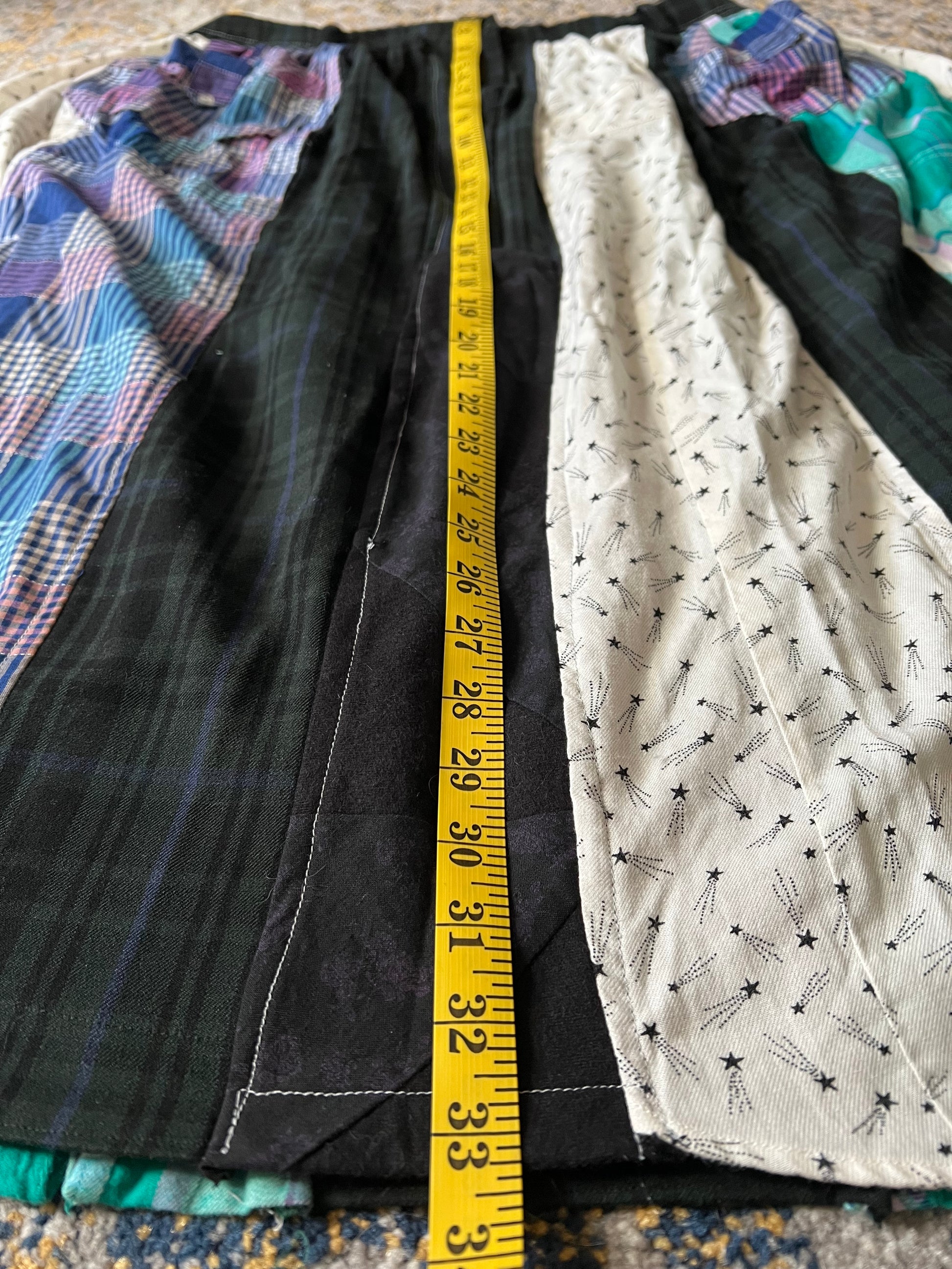 Fabric with a pattern of stars and lines, measured with a tape measure on a textured surface.