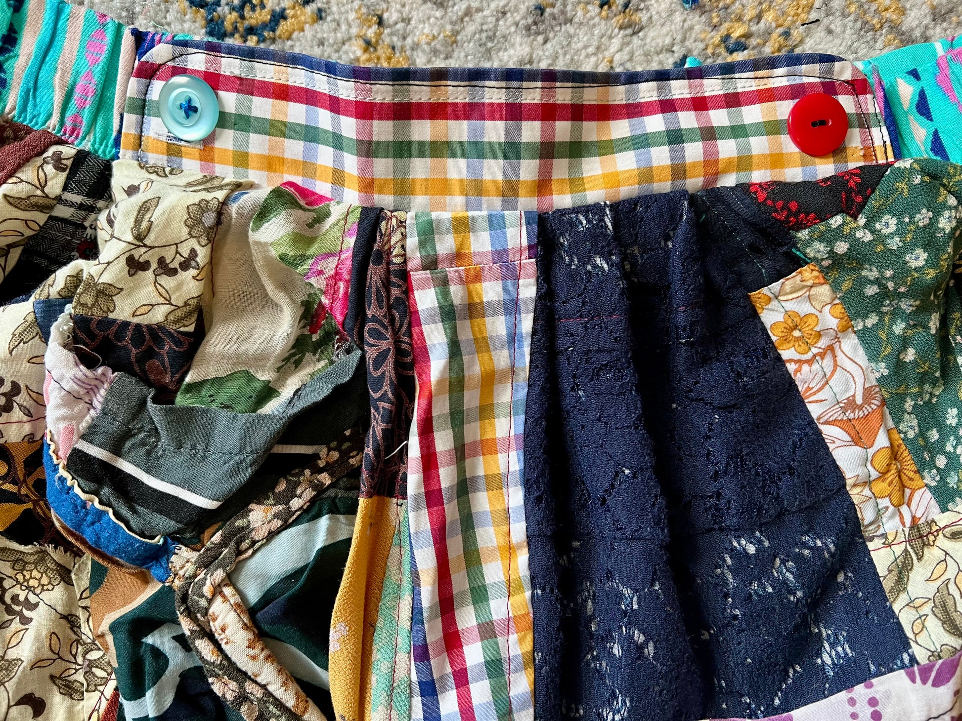 Collection of colorful fabric pieces with a focus on a plaid patterned fabric.