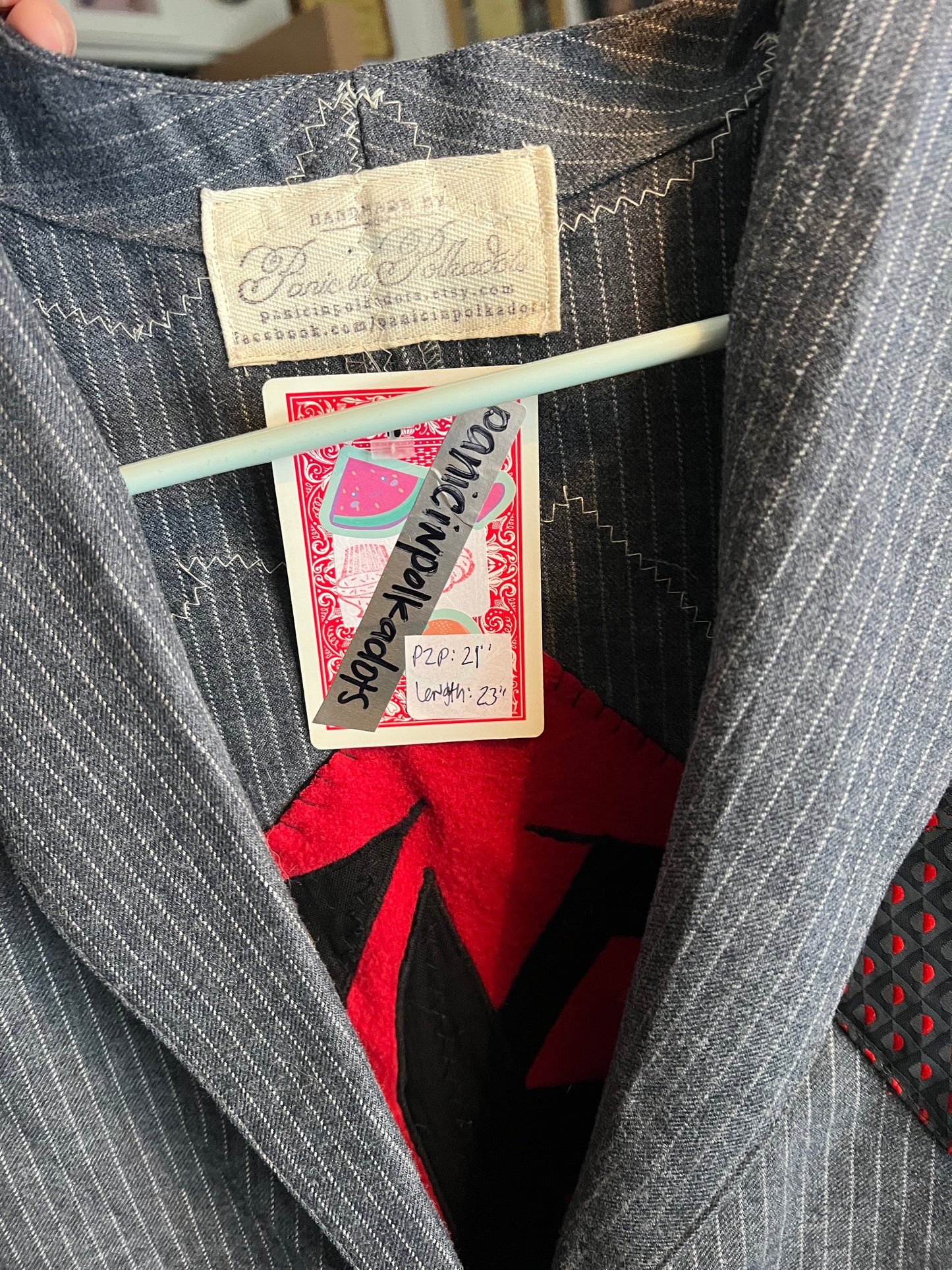 Close-up of a suit with vintage labels and a red patterned fabric underneath.