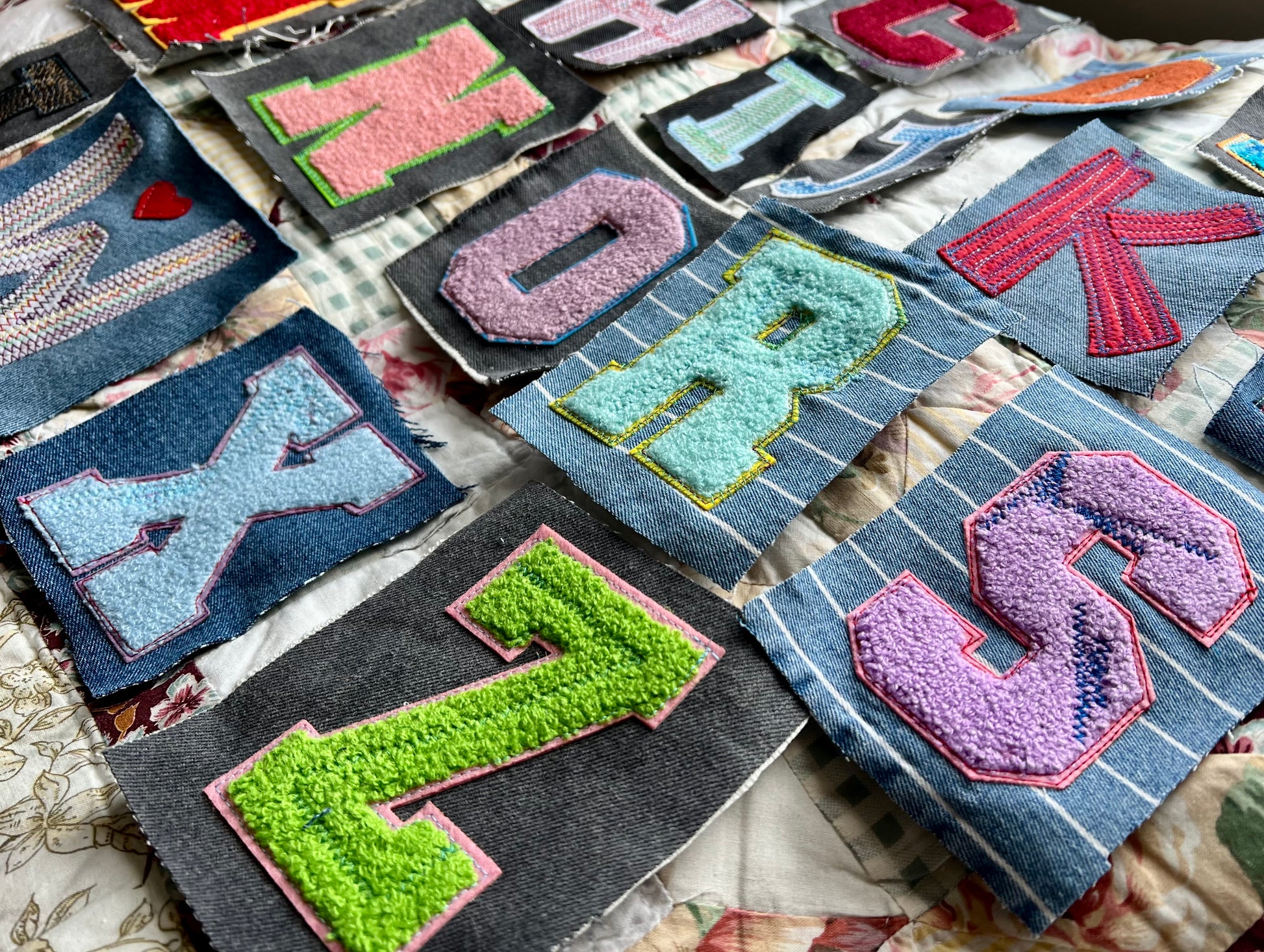 Collection of colorful embroidered patches with letters on a textured surface