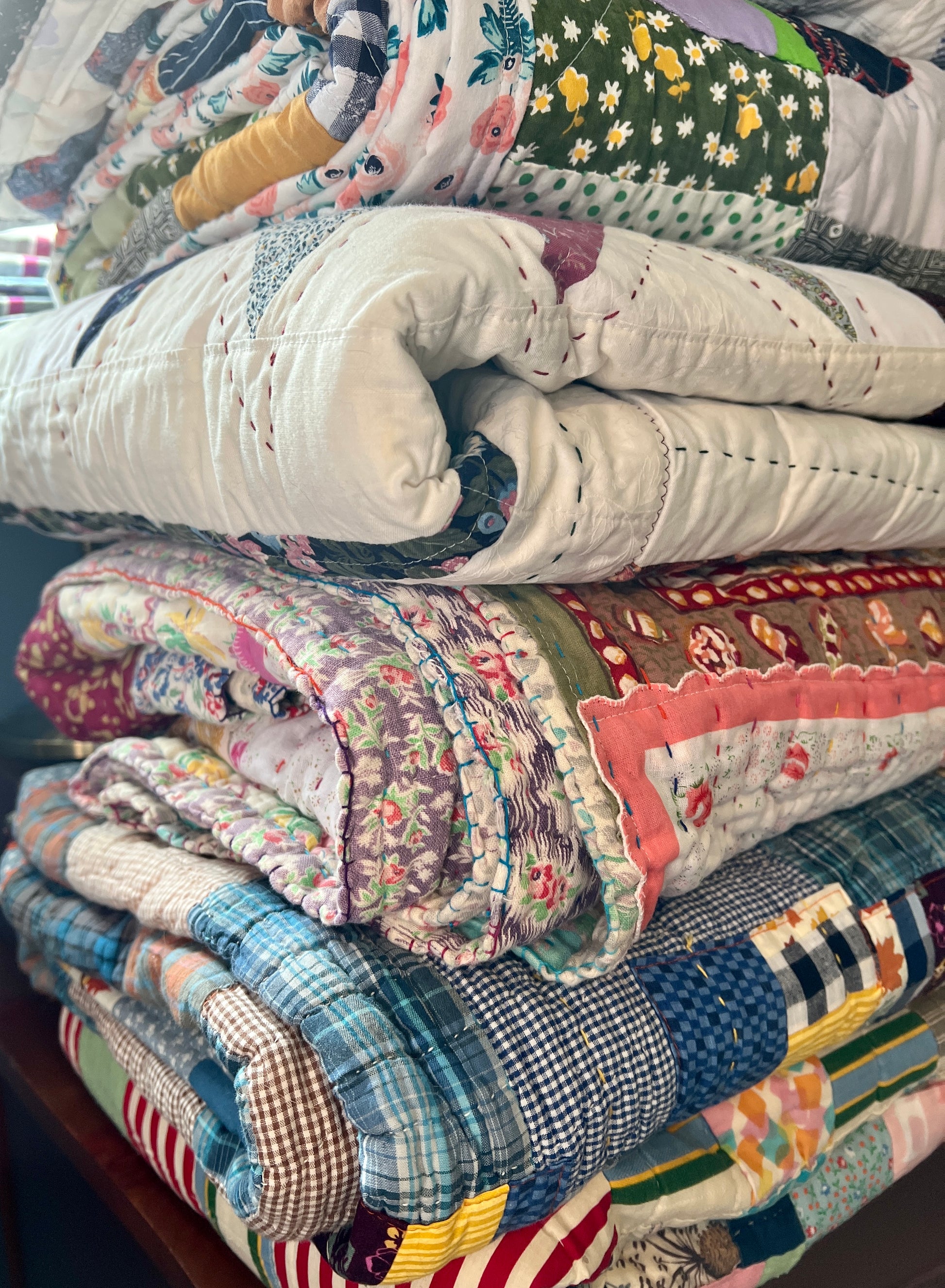 Stack of colorful quilts with various patterns