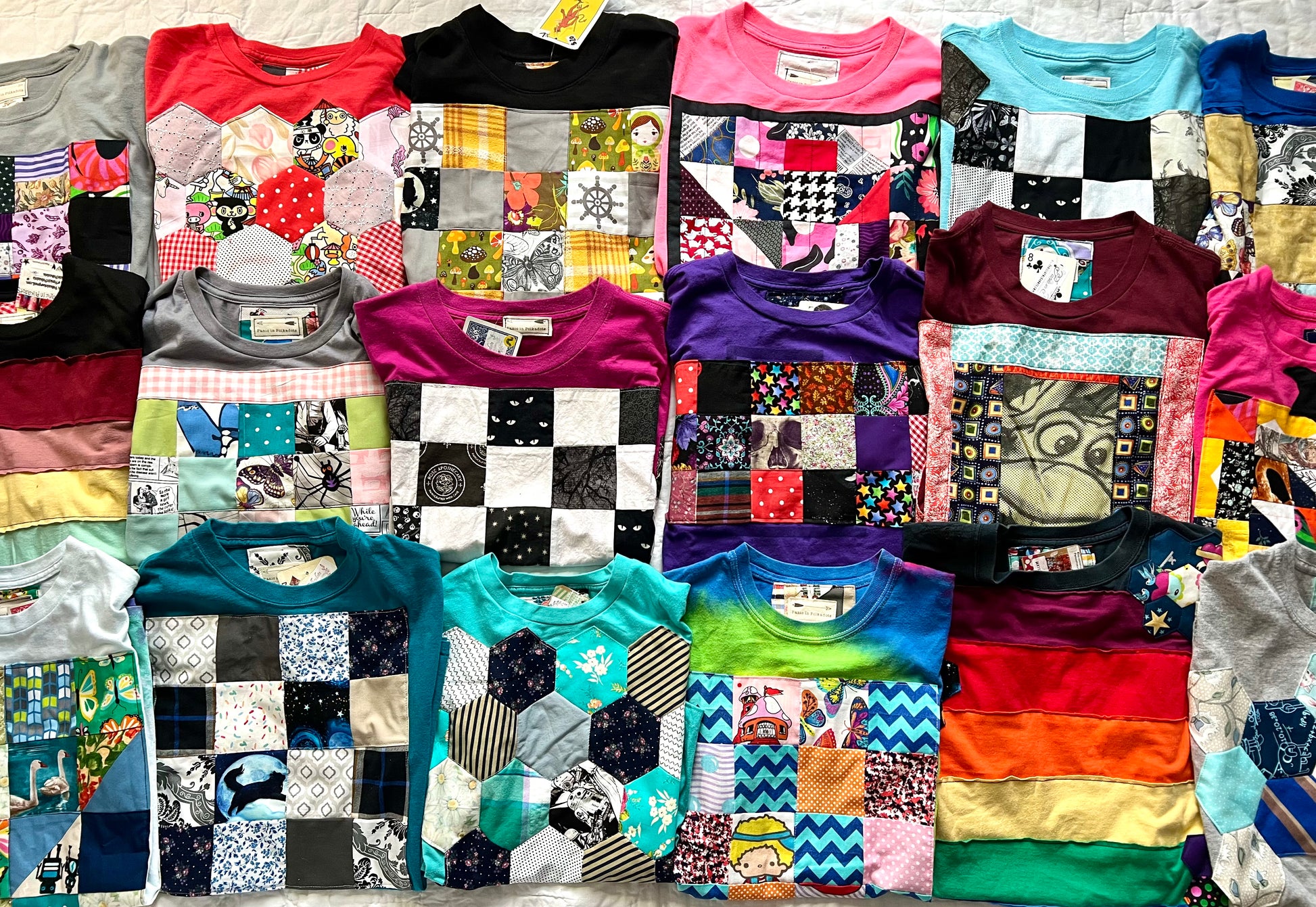 Collection of variously patterned t-shirts folded and displayed in a grid.