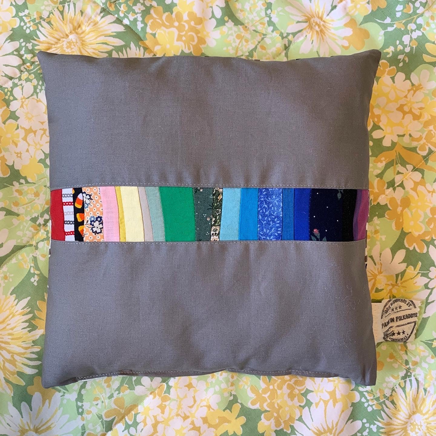 Rainbow Stripes little pillow, aerial view against a bright floral background