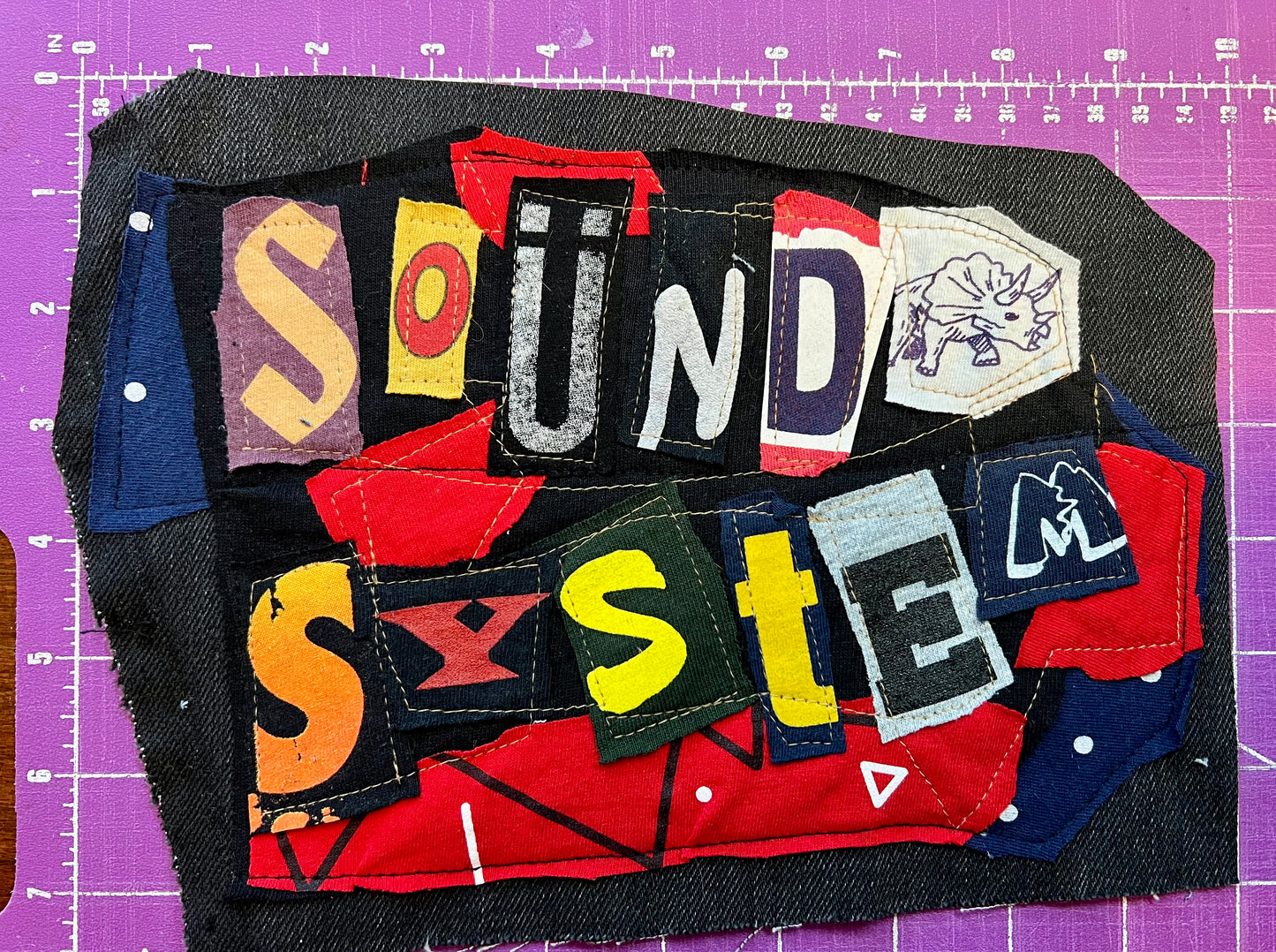 Fabric patch with 'Sound System' text on a purple grid background