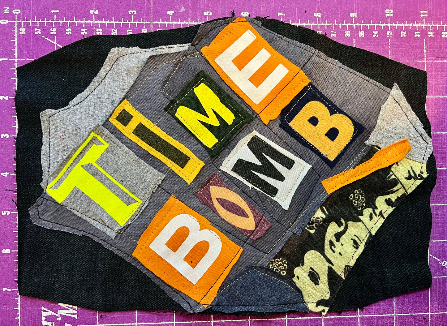 Fabric patch with 'TIME BOMB' text on a purple cutting mat