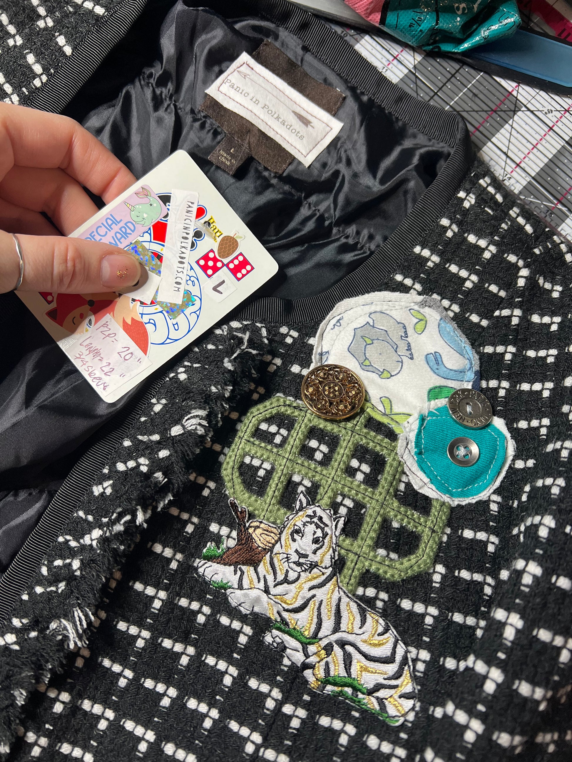 Hand holding a card with a colorful design on a textured black and white fabric background