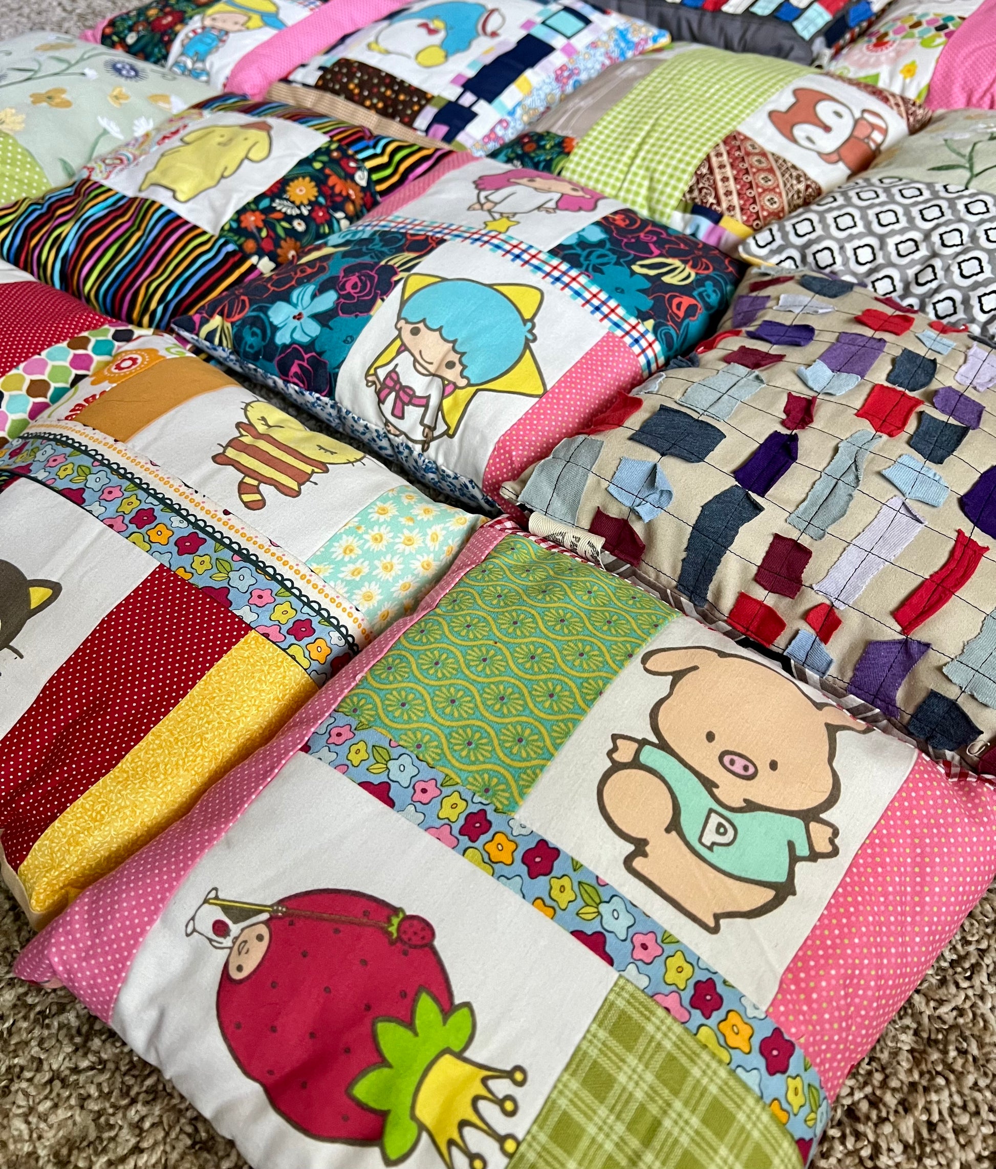 A close-up of a grouping of colorful patchwork pillows, featuring various cartoon and floral patterned fabric.