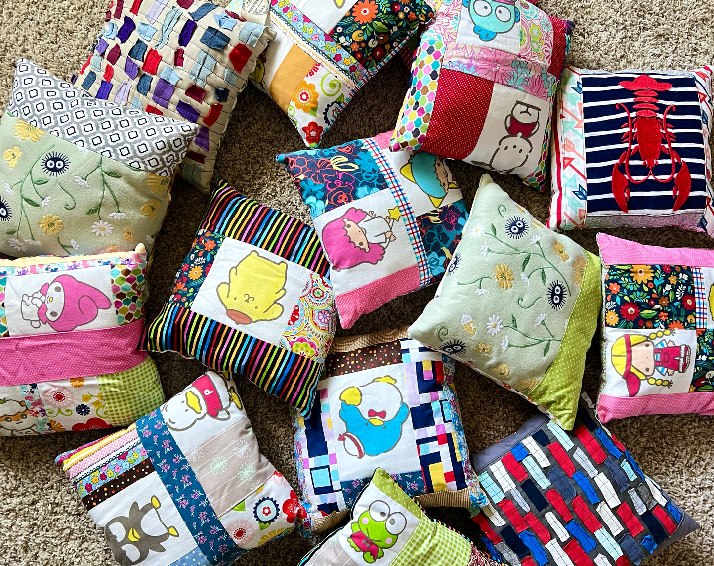A collection of colorful handmade patchwork pillows with various cartoon and floral prints, arranged on a beige carpet.