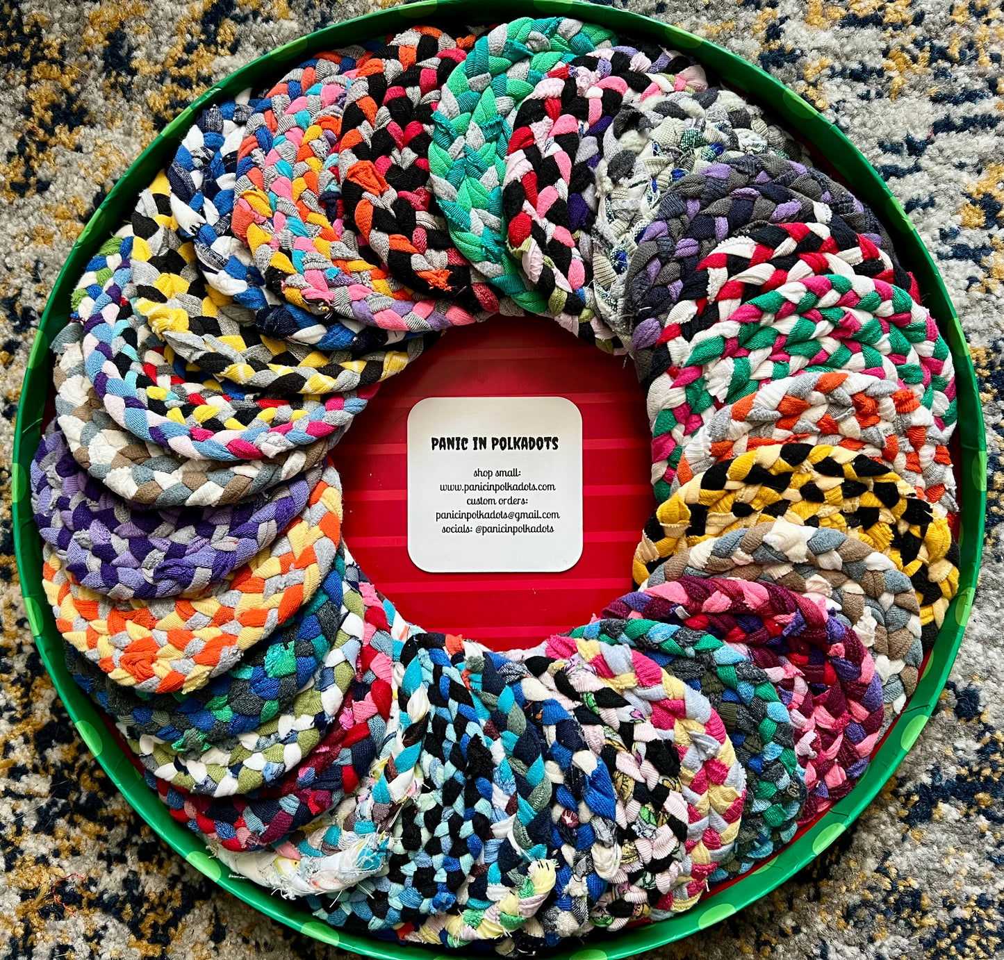 Colorful braided coasters arranged in a circular pattern on a textured surface.