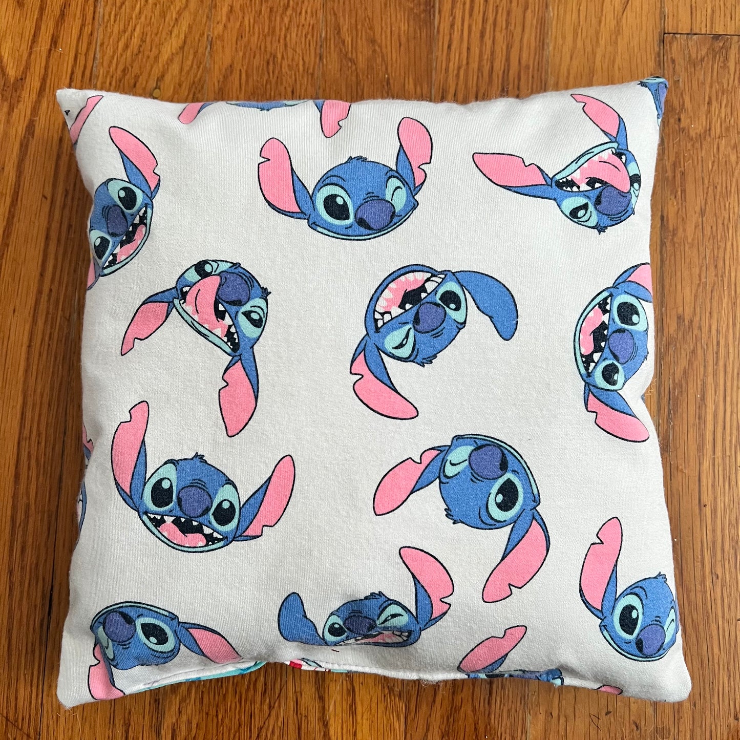A tooth fairy pillow featuring very cute stitch design aerial view against a wood background