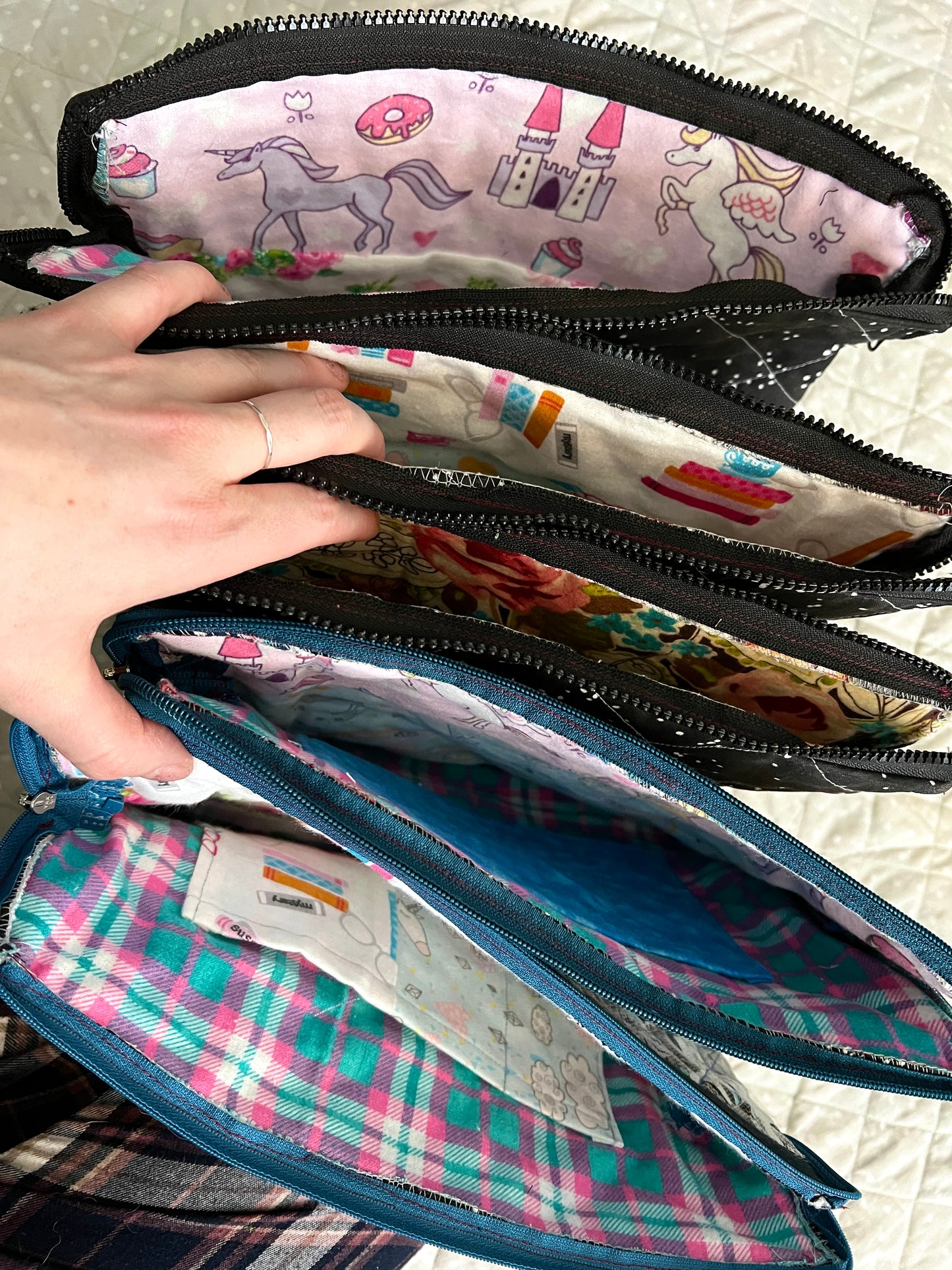 A hand holds open all ipad tablet cases, zippers open to see inside
