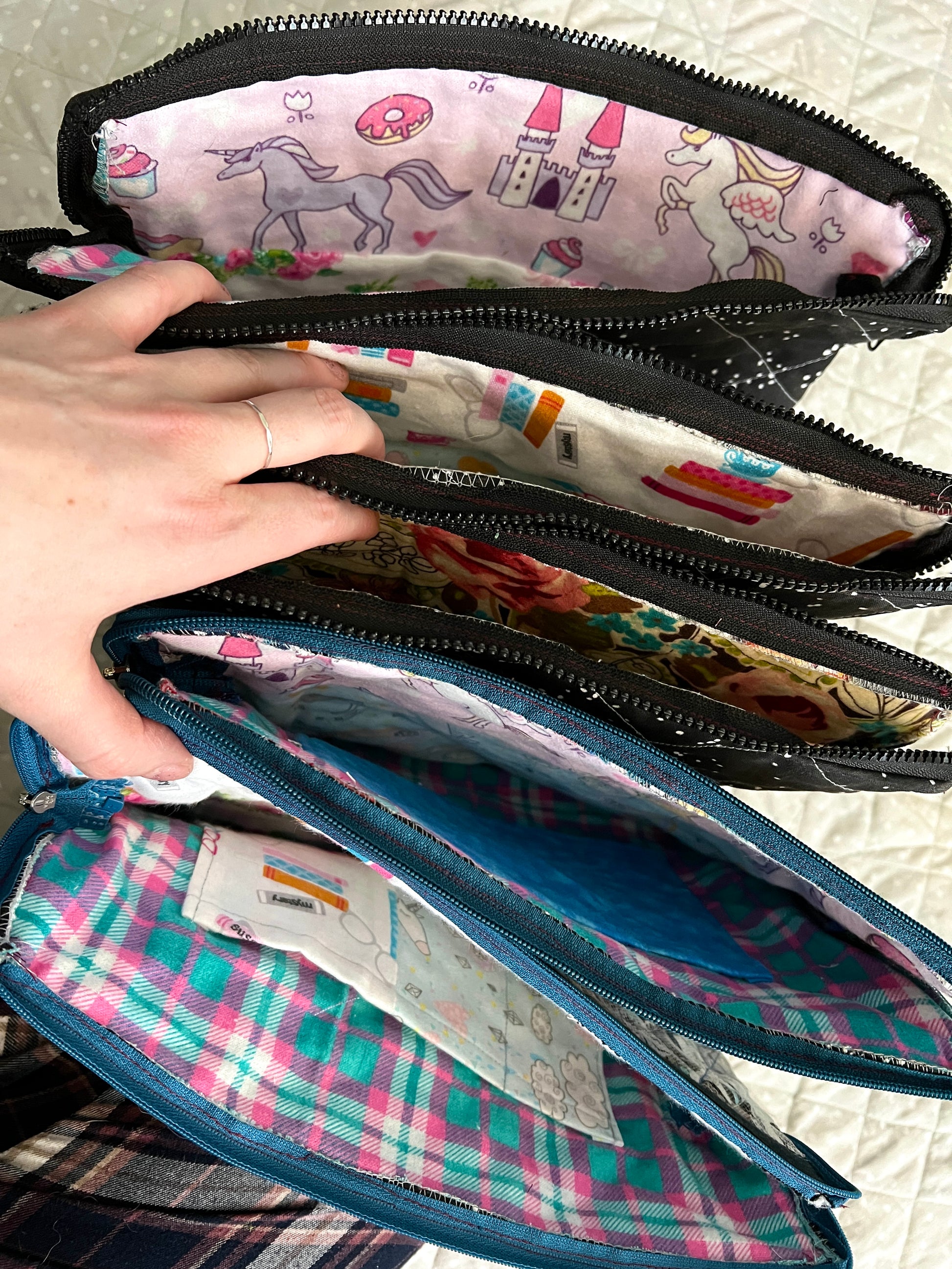 A hand holds open all ipad tablet cases, zippers open to see inside