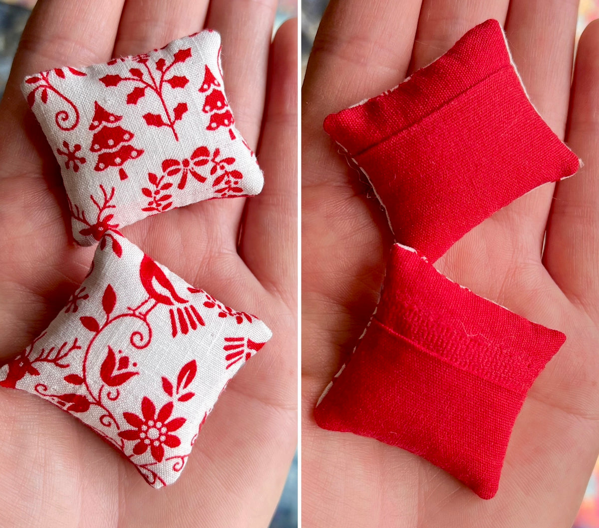 Two small fabric pillows, front with red floral patterns on white and the back solid red, held in hands.