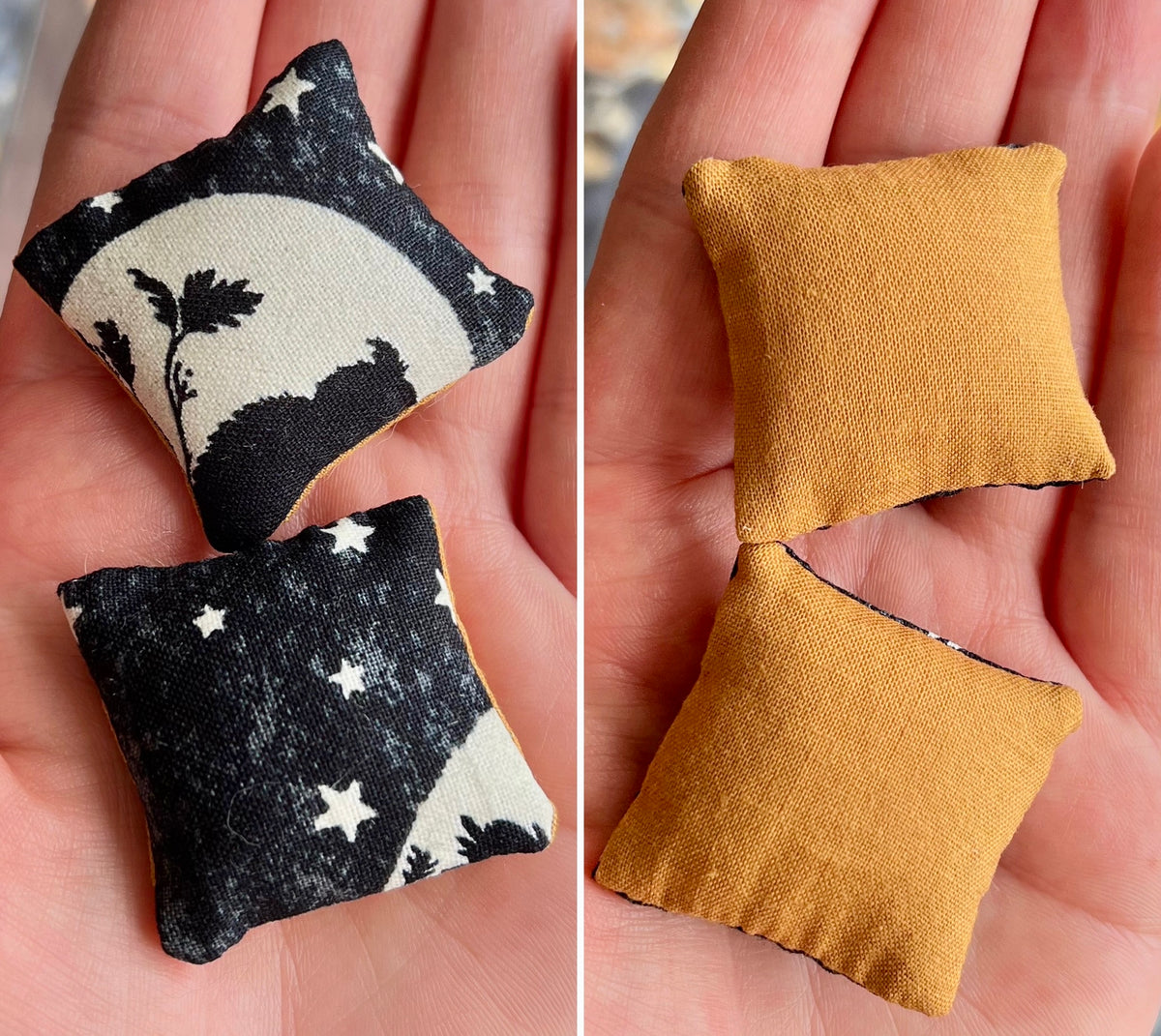 Two small fabric pillows, front black with white patterns and back mustard yellow, held in hands.