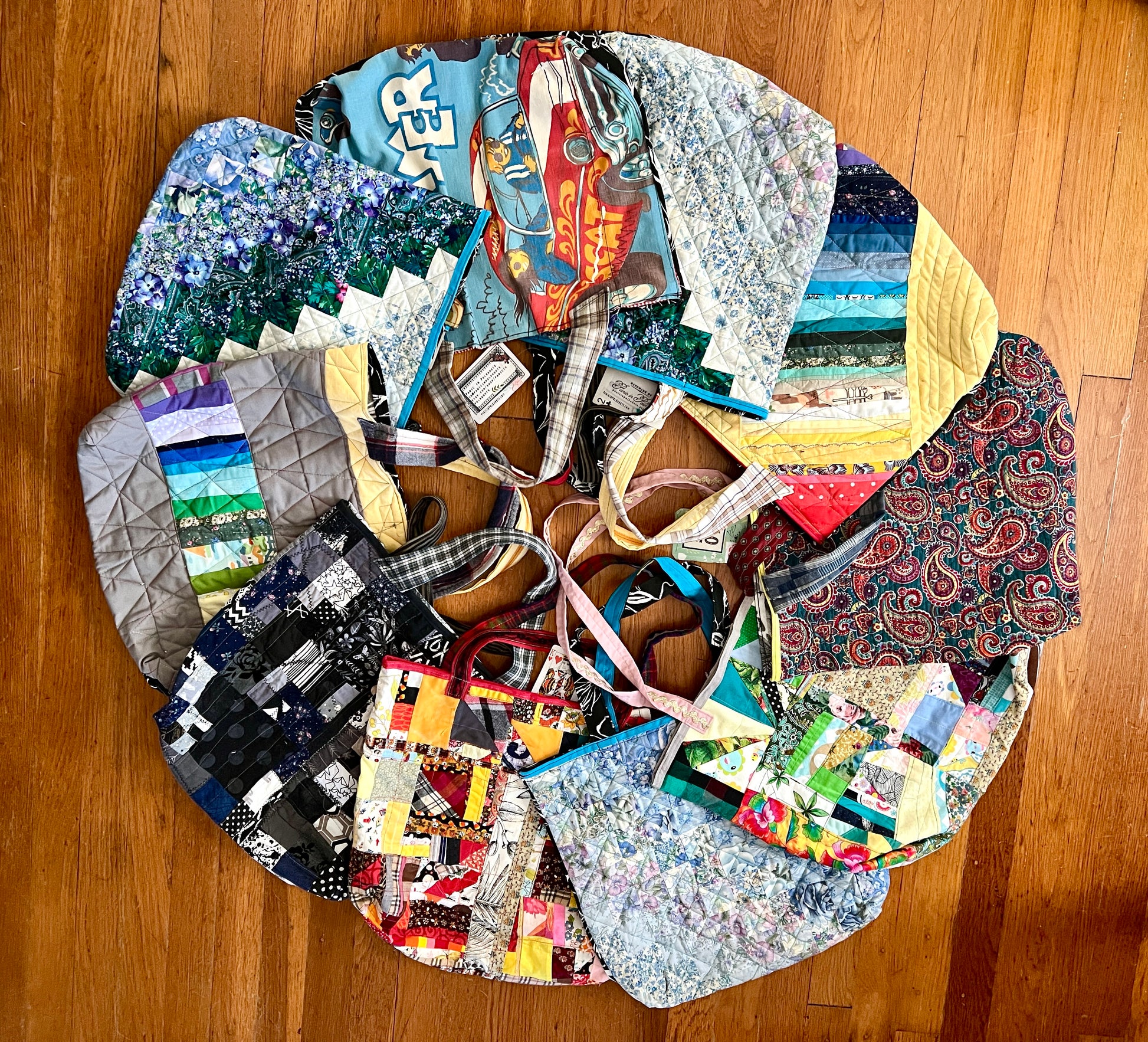 Tote bags, made from scraps and quilts, assortment in a circle array on wood floor