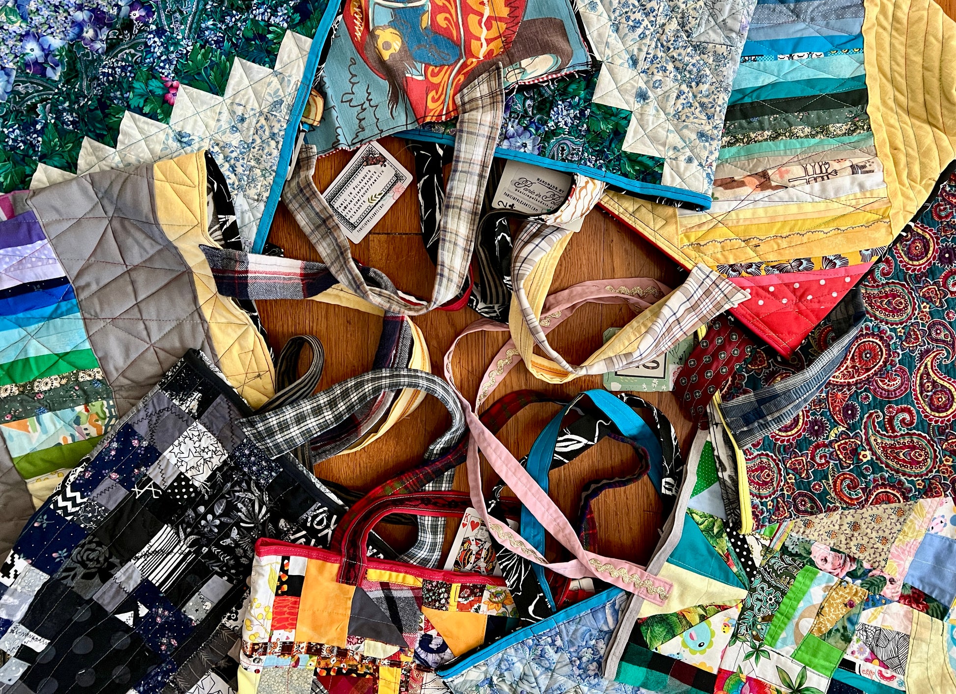 various handmade tote bags, in a circle with the handles meeting in the middle