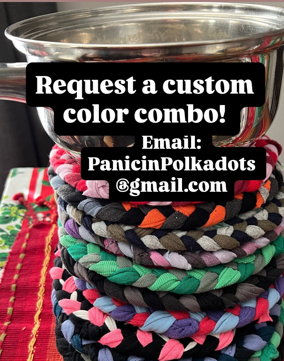 Stack of colorful braided mats with a metal pot on top, promotional text overlay “request a custom color combo’