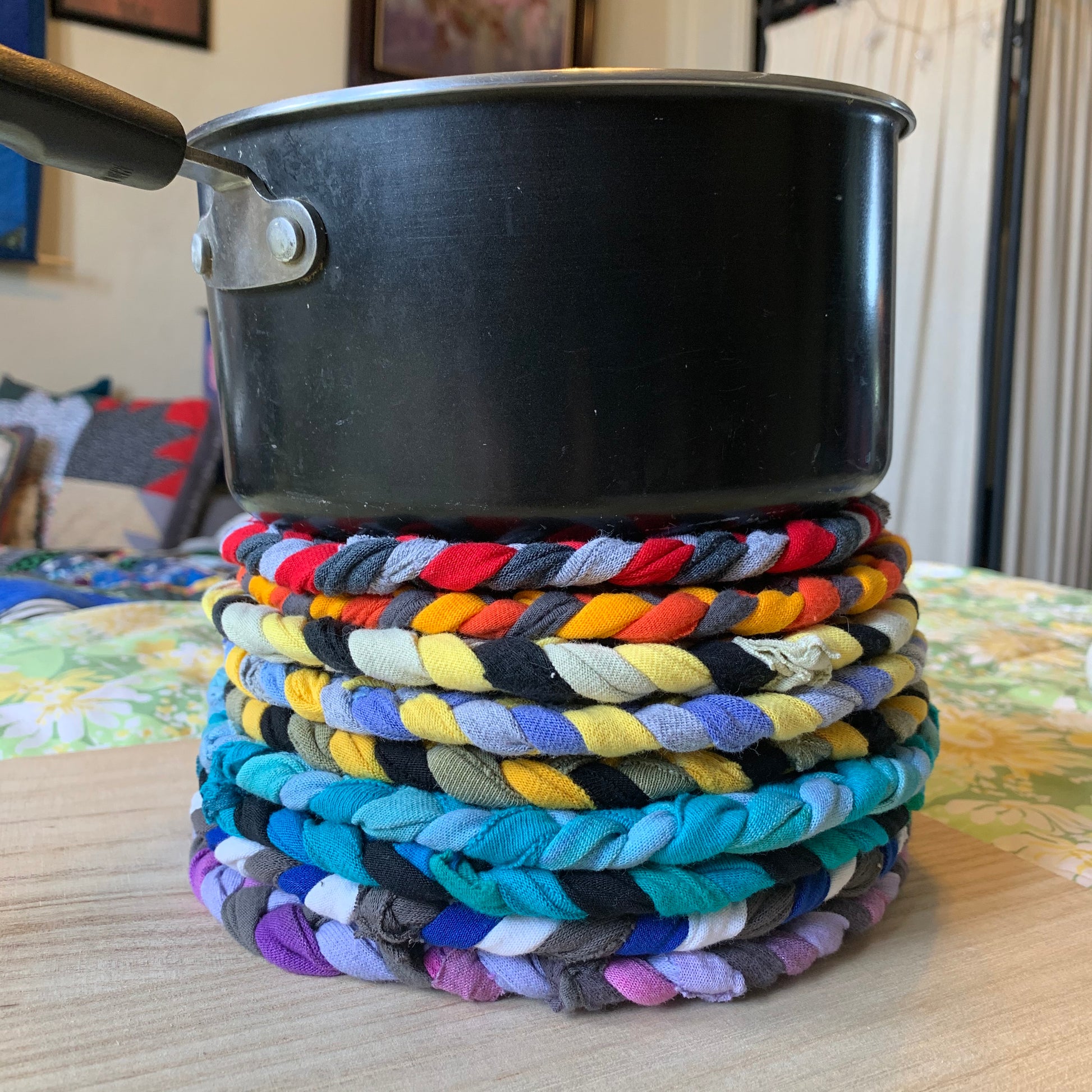 Trivet potholders, hand braided, stacked under a sauce pan for usage and scale