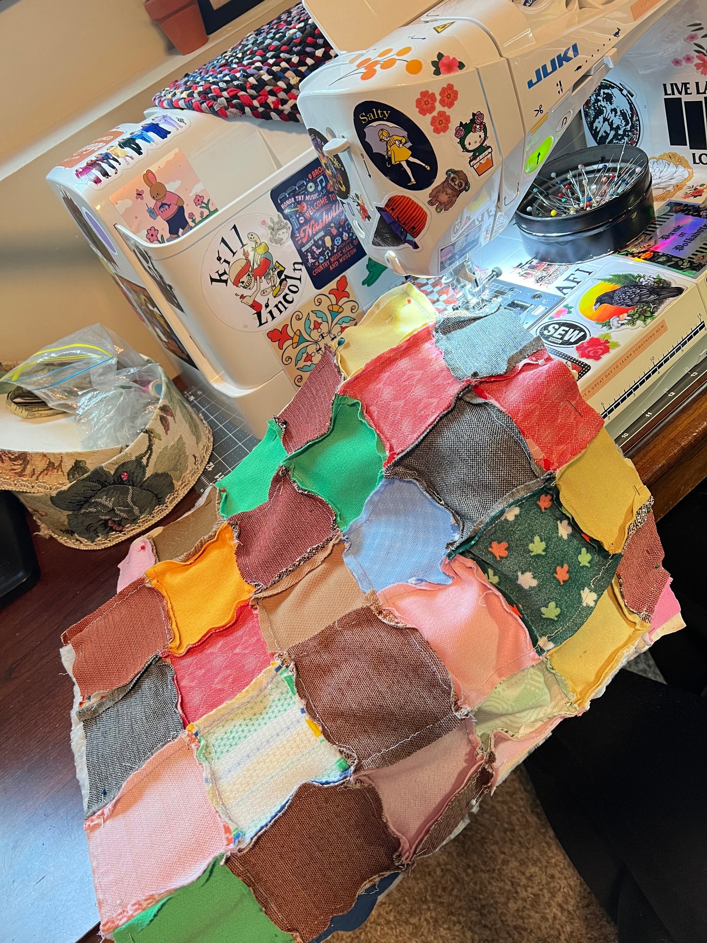 Vintage quilt as a work in progress to become a tote bag. Bag is pictured on a sewing machine, under needle. Other notions and supples are also seen.