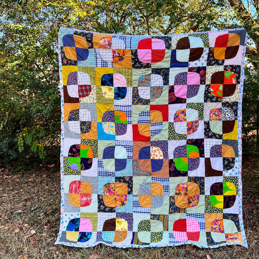 A Vintage Quilt, Neon Snowballs design, held up outside with fall leaves all around