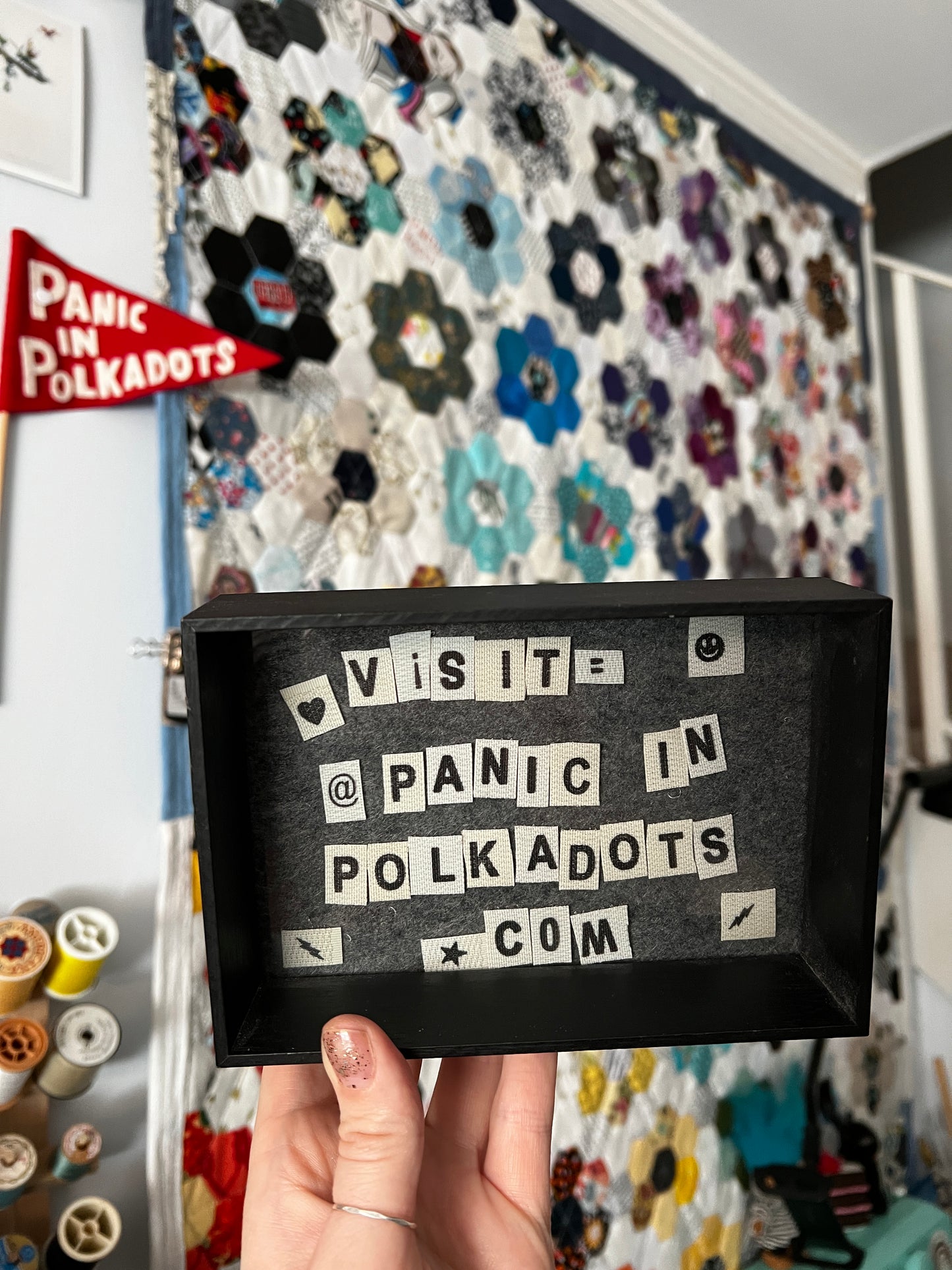 Black box with text held over a colorful fabric background
