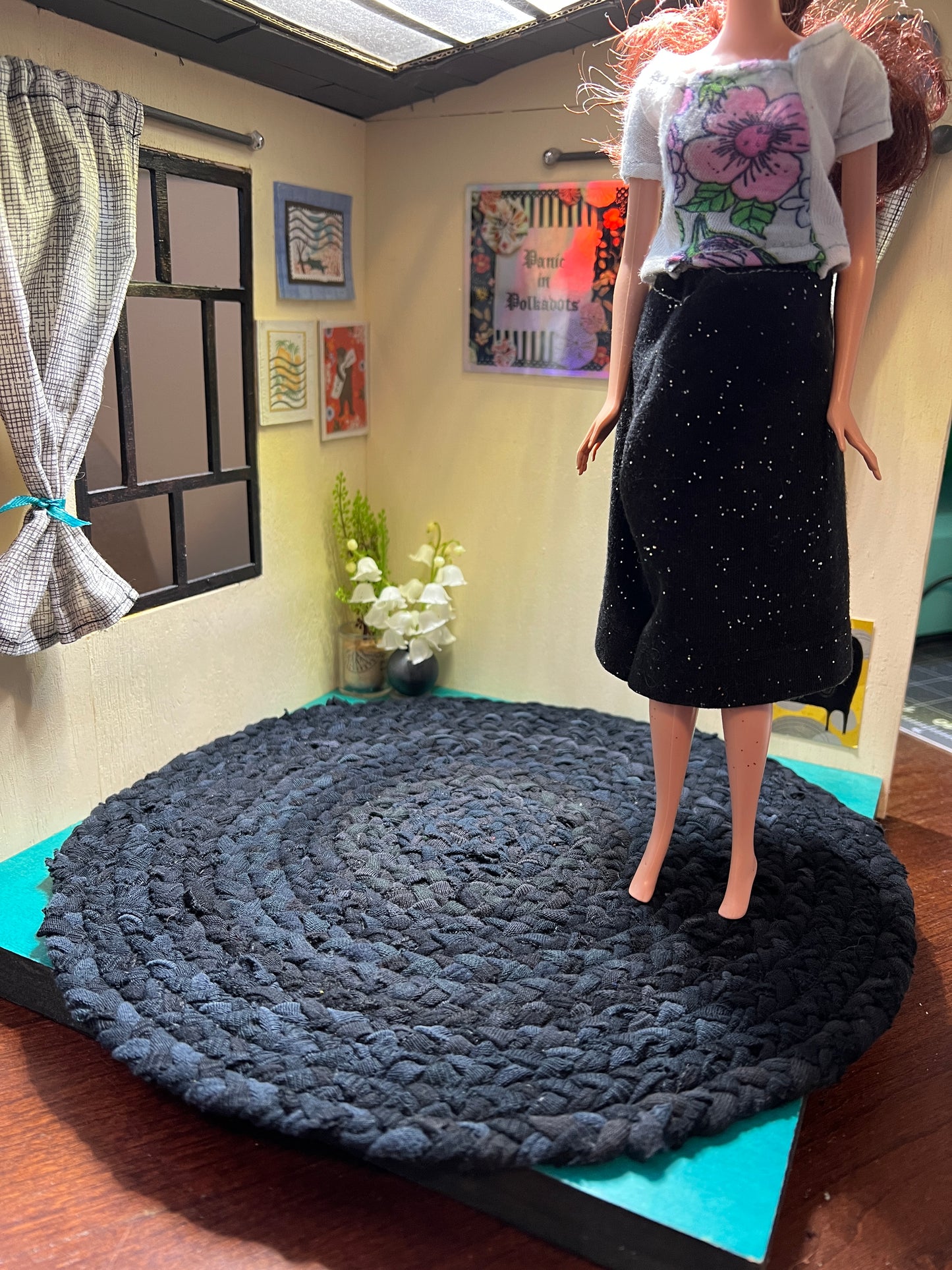 view of miniature rug in a room box, with Barbie standing atop the 11" all black rug for scale and display ideas