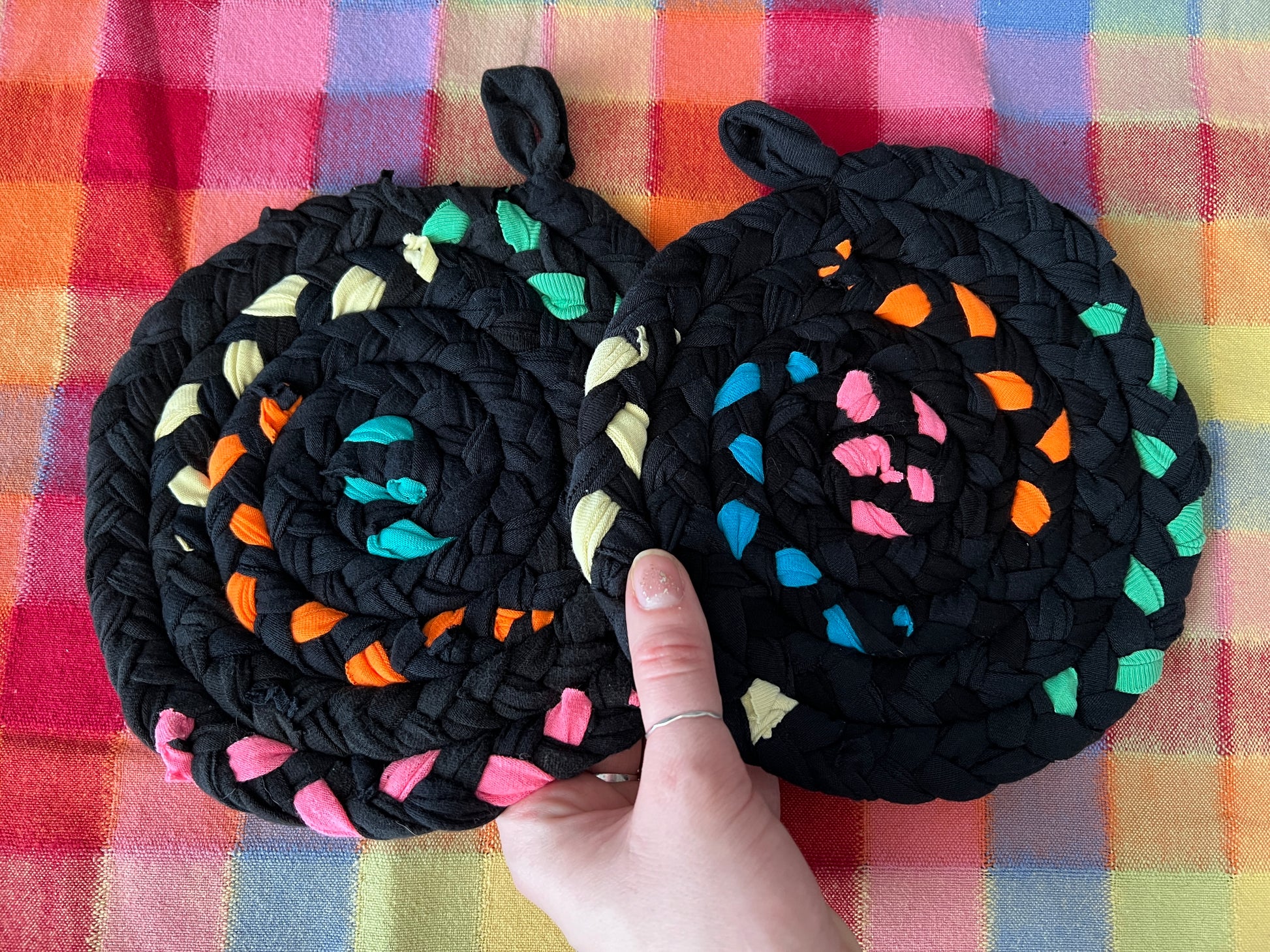 black neons potholder set, in hand for scale, against a colorful background