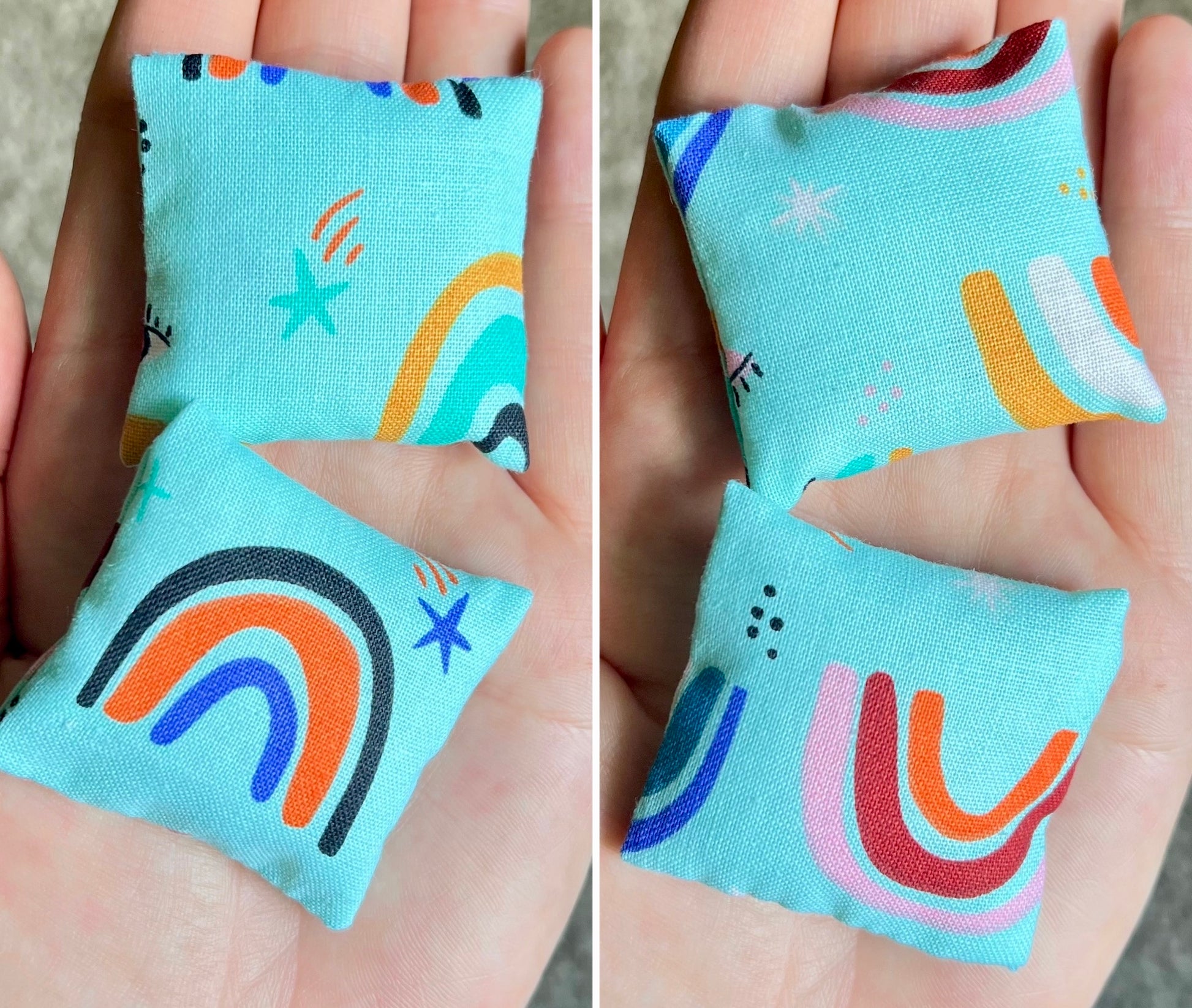 Two small fabric doll pillows with colorful  rainbow designs held in hands against a neutral background.