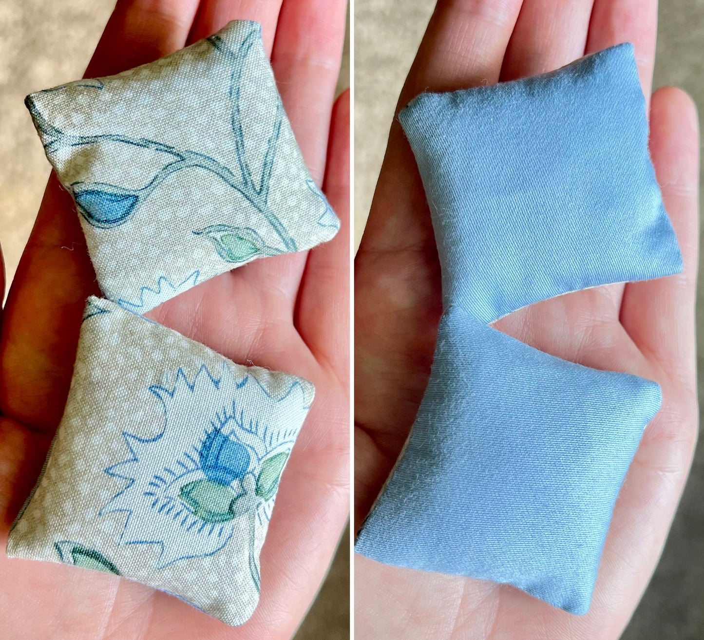 Two square fabric pillows held in hands, front with floral patterns and the back is solid blue.
