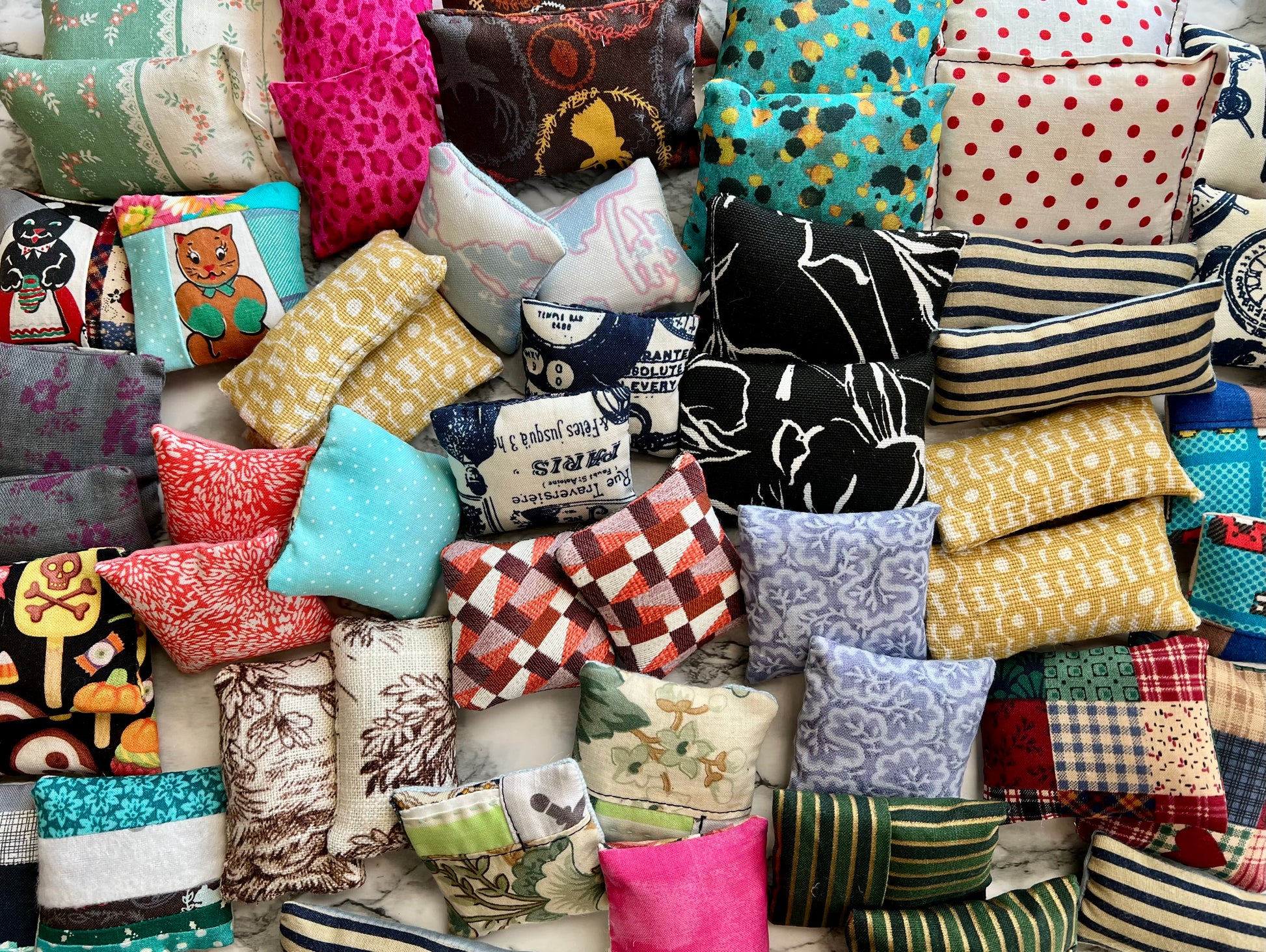 Collection of various colorful miniature dollhouse pillows arranged together