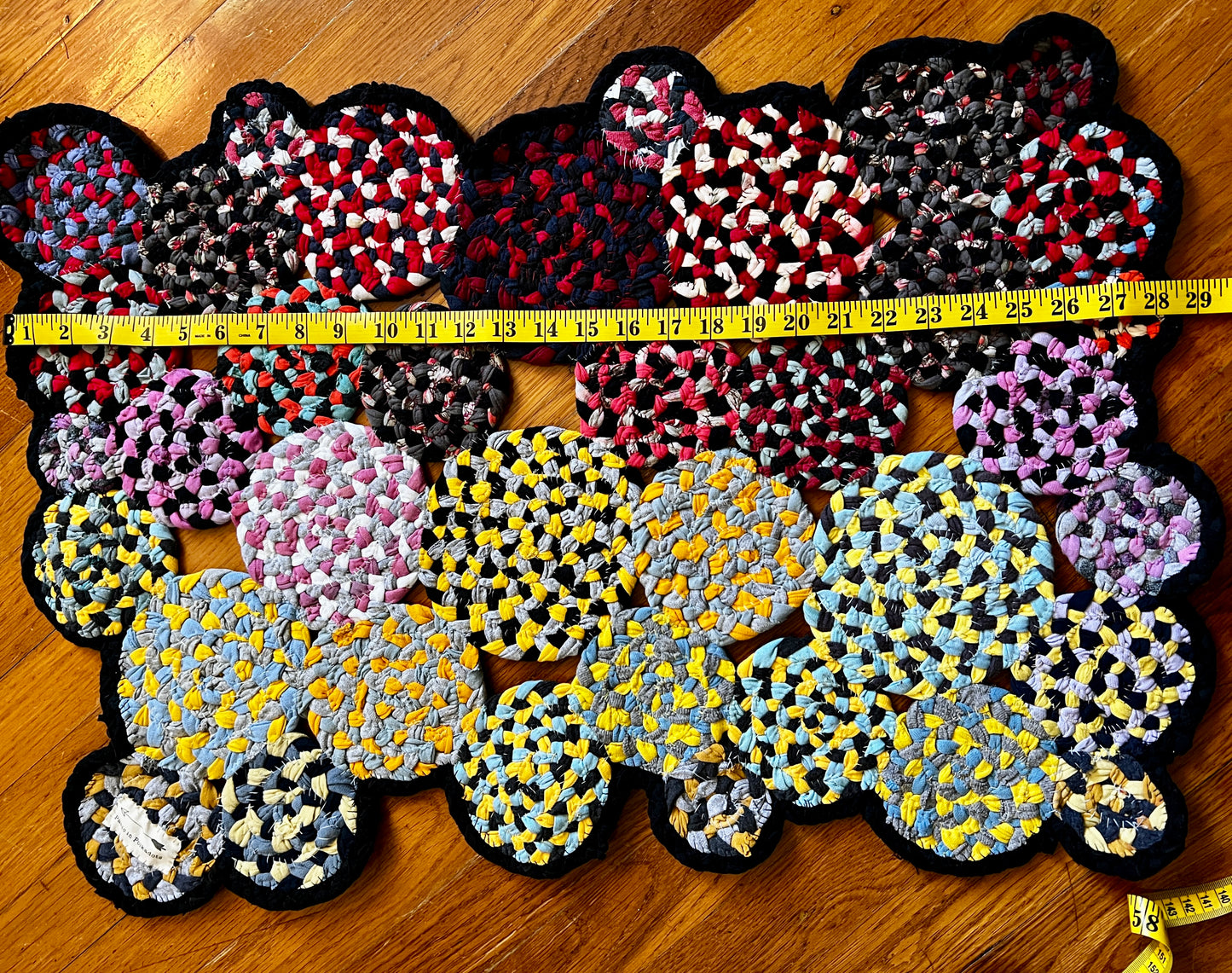 doormat rug shaped in yellows and pinks, measuring tape across length