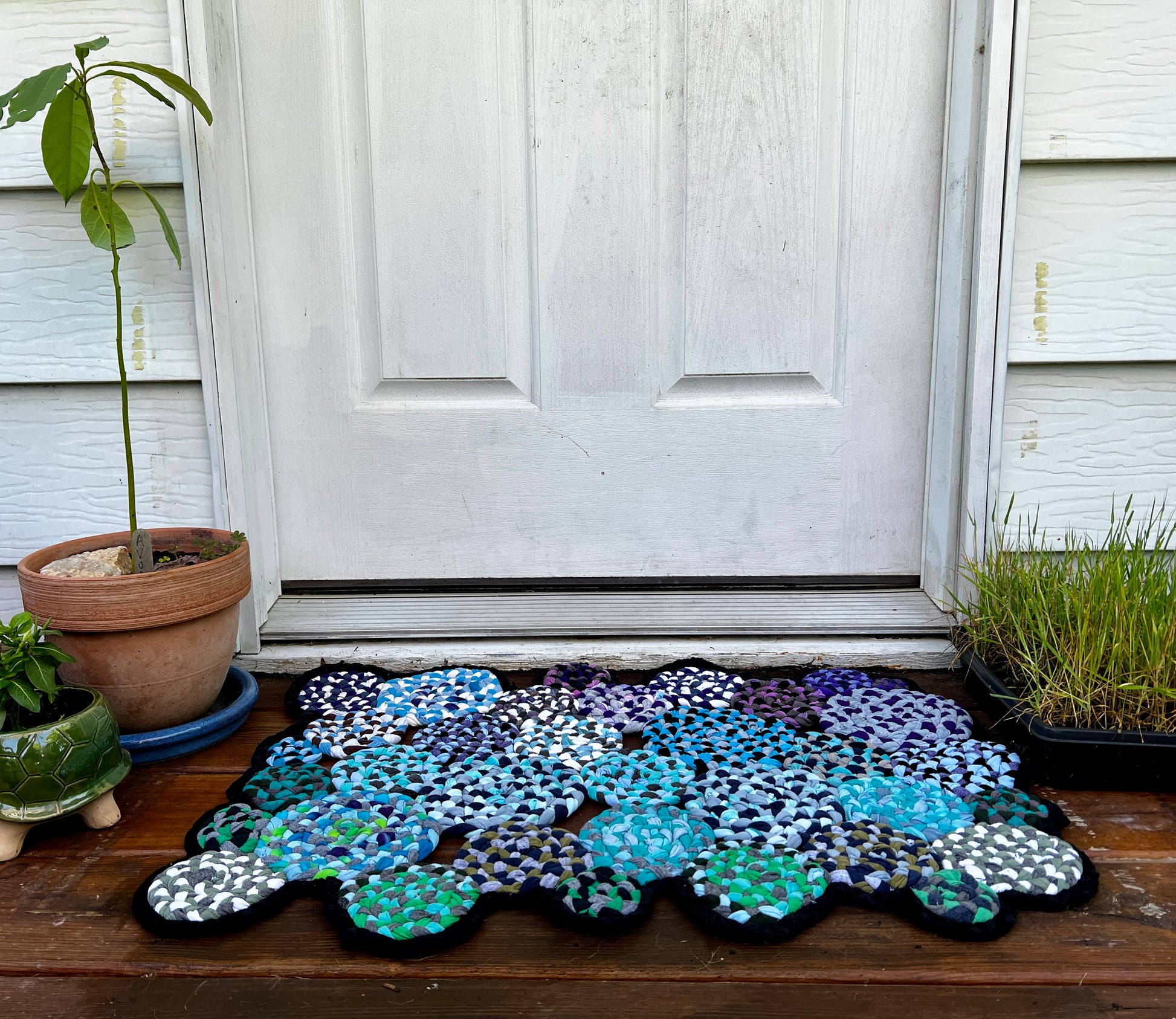 doormat tshirt rug back door on a wood deck, surrounded by plants