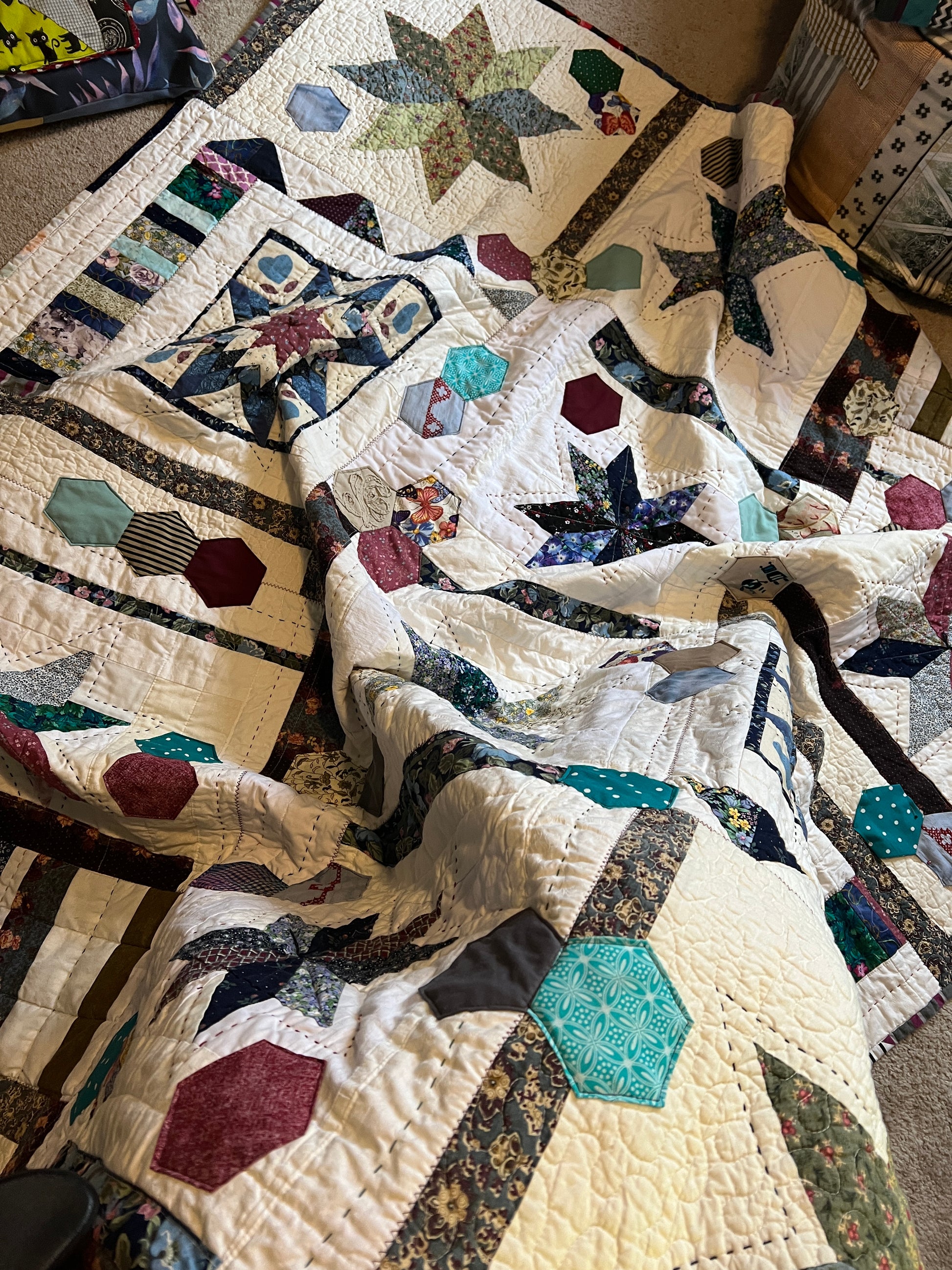 A quilt with eight point stars and quilted hexies, cascading from the lap downto the floor