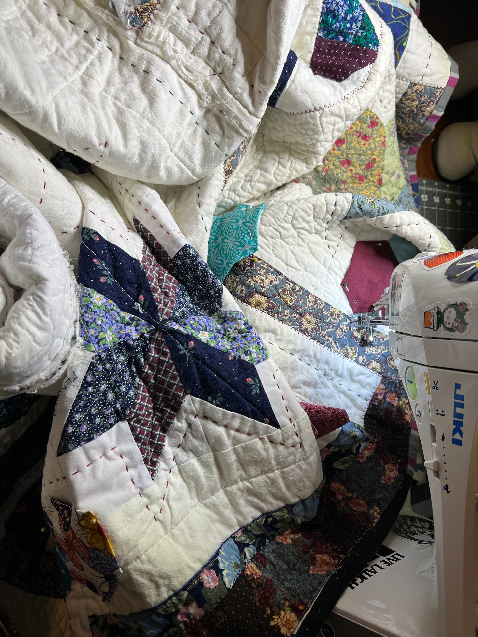 A quilt with eight point stars and quilted hexies, as a work in progress on the sewing machine
