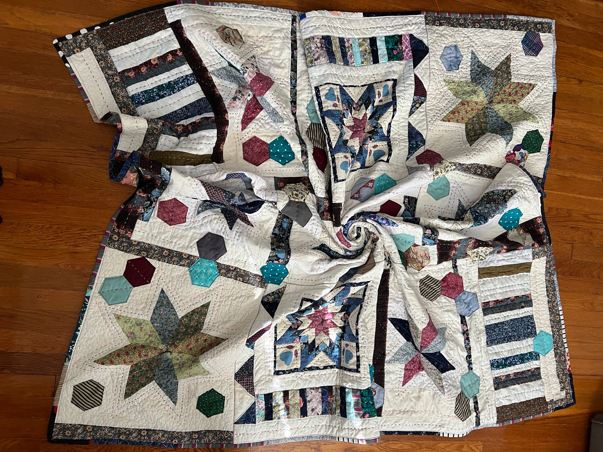 front of stars and hexies quilt, lay flat on a wood background, swirled in center to show texture