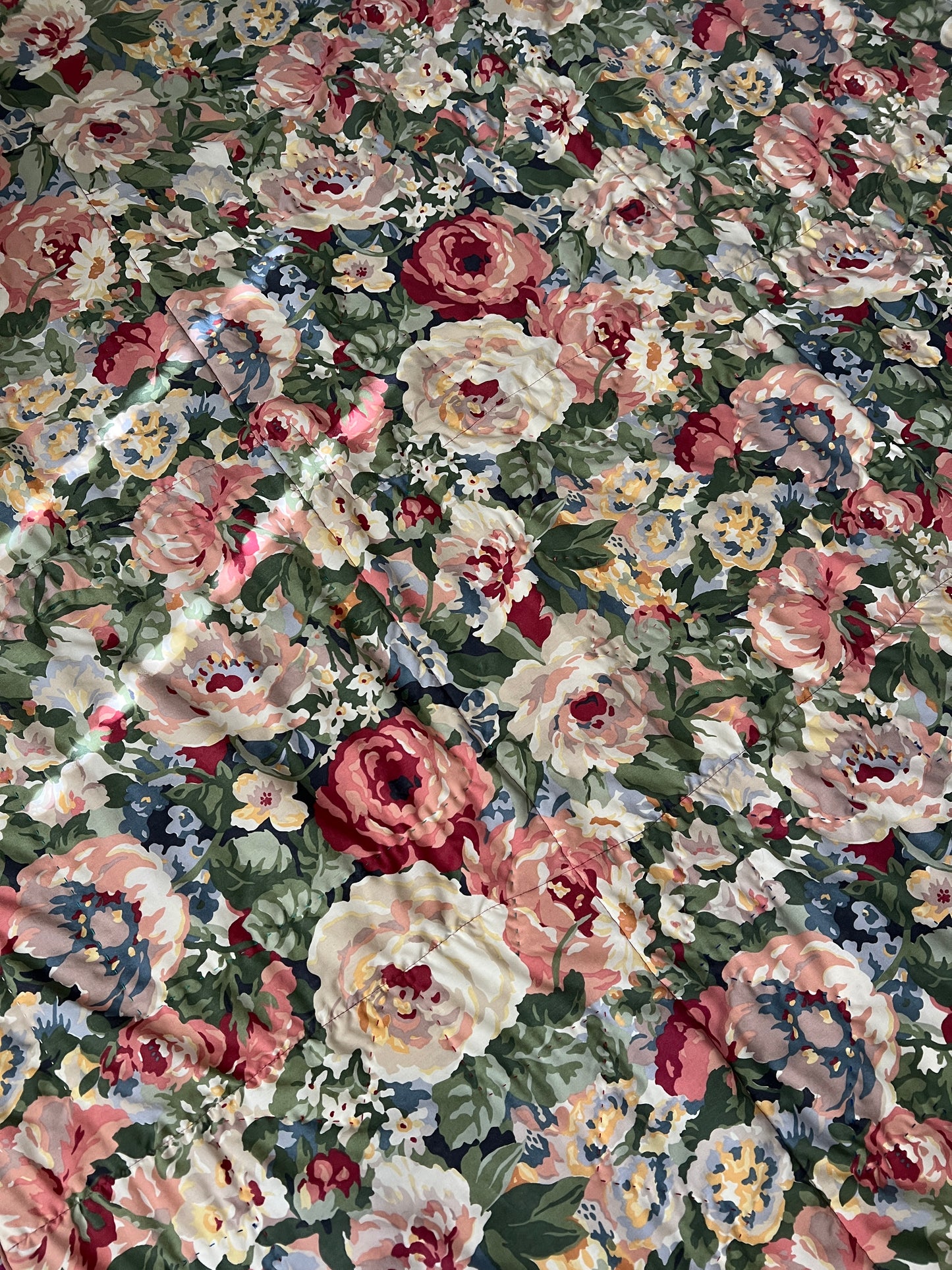 A quilt with eight point stars and quilted hexies, showing off the vintage floral back