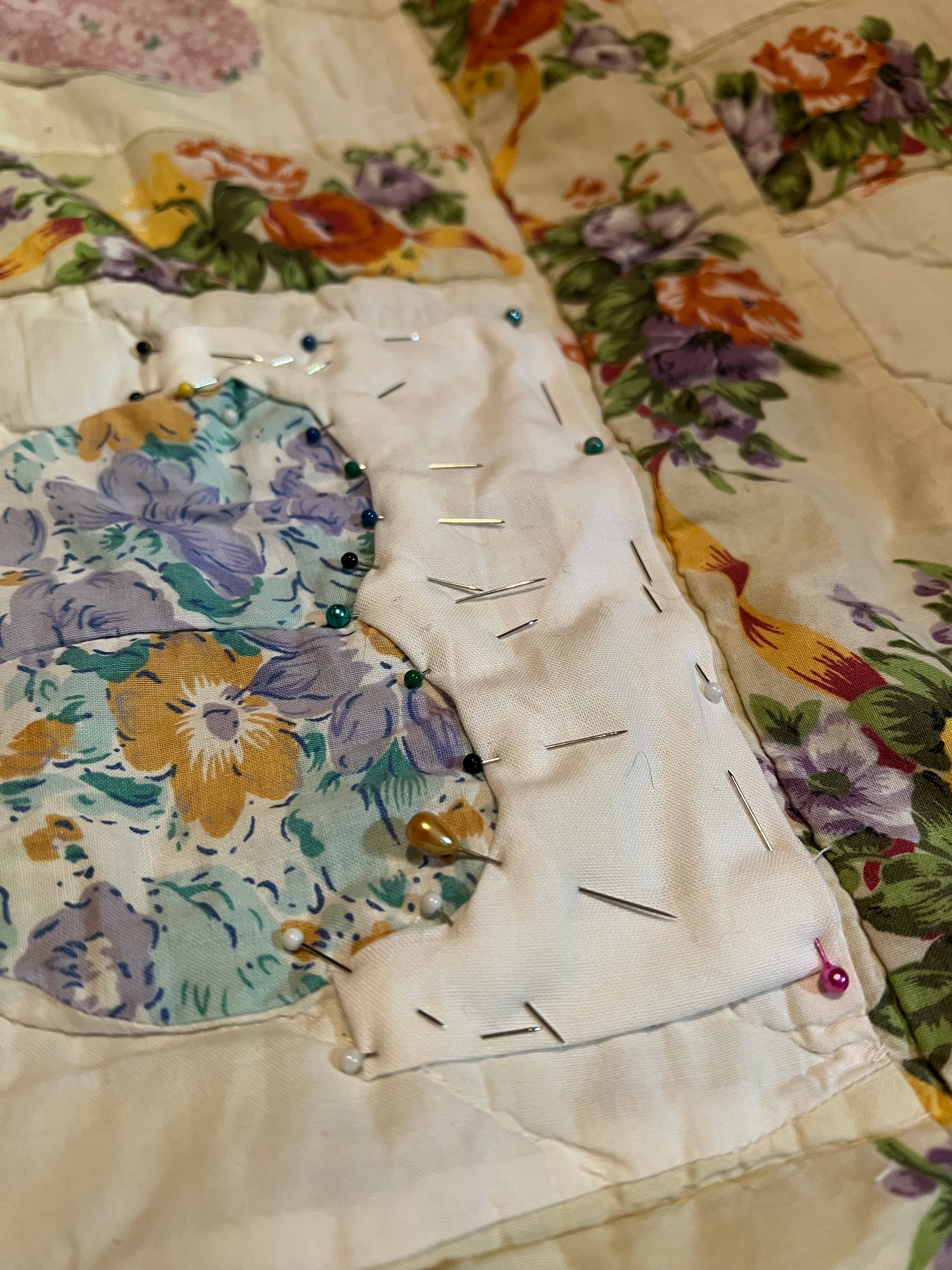 work in progress of the applique of white over the stained portion of quilt, various pins holding appliqué in place