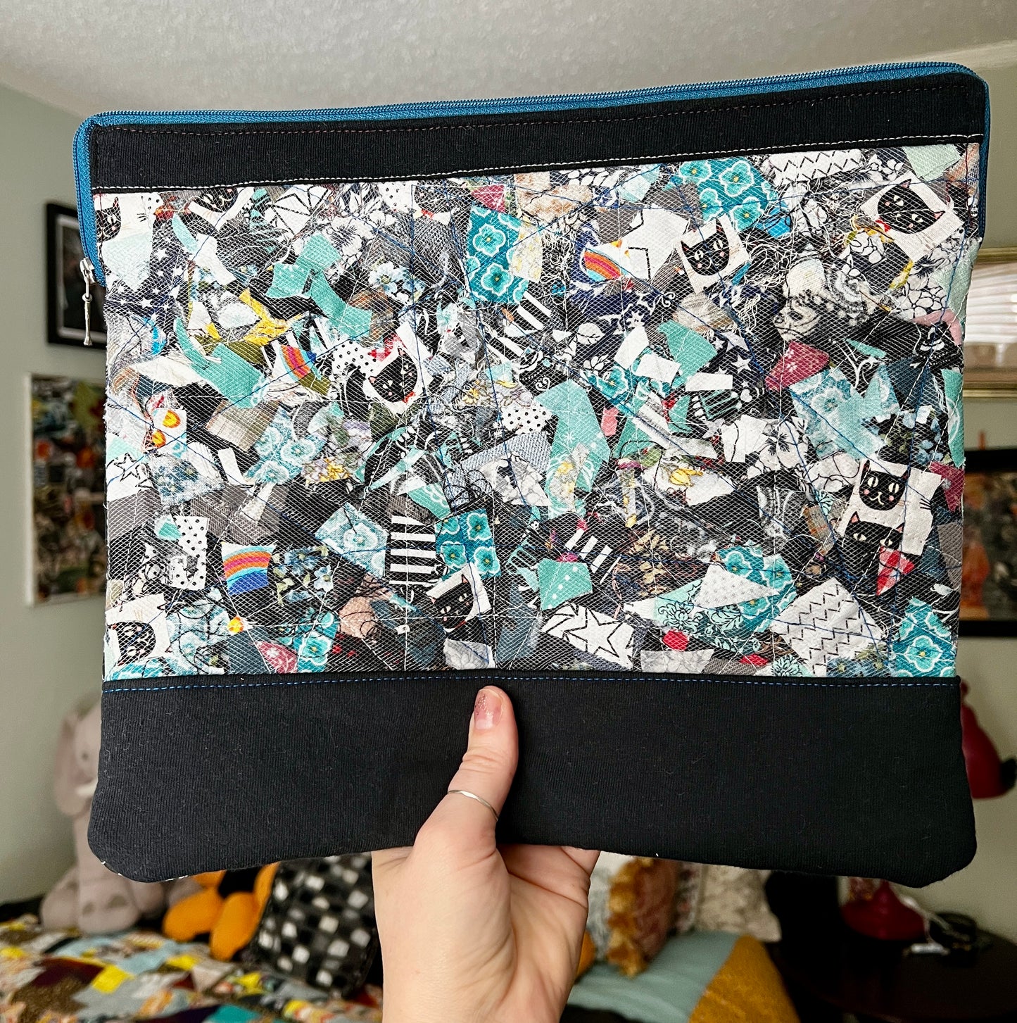 ipad case, held up for scale, created from fabric scraps under a tulle layer, zipper closure, padded, with inside pocket