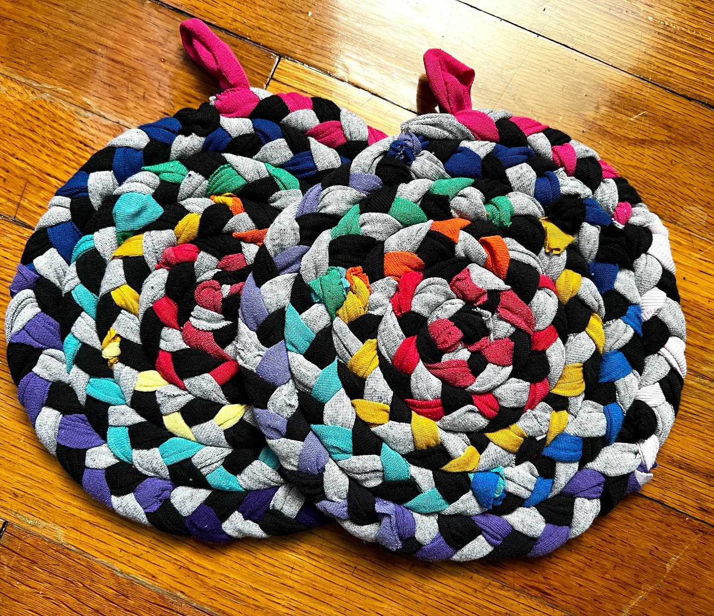 a set of two handbraided and handsewn potholders against a wood background