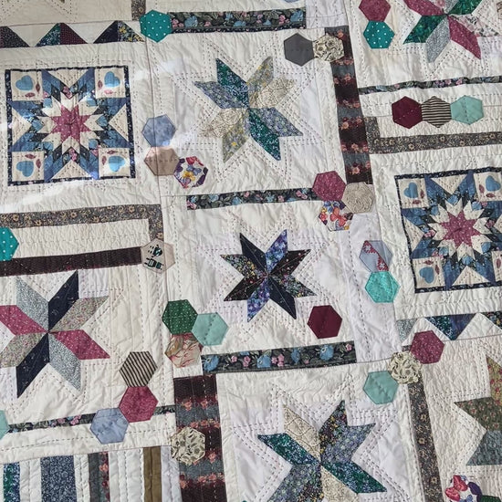 A quilt with eight point stars and quilted hexies, as the camera pans across the front of the quilt