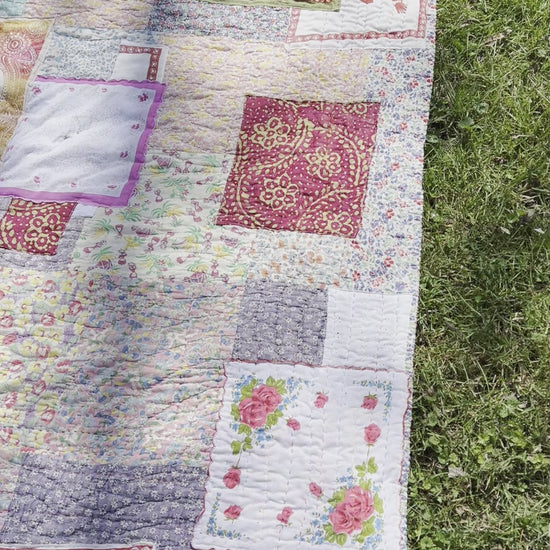 a video of the quilt, outside against a green lush background, birds chirping in distance