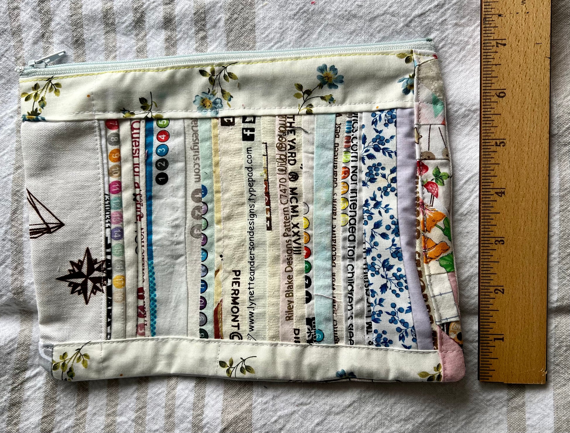 scrappy selvedge zipper pouch, with a ruler off to the side showing the width to be about 7 inches